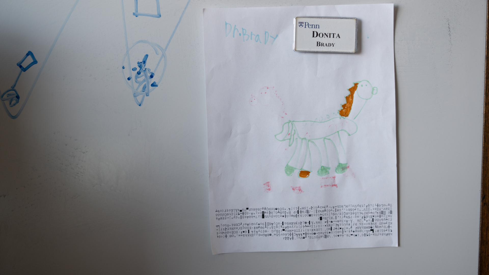 A drawing made by a child, held by a magnet, on a whiteboard.