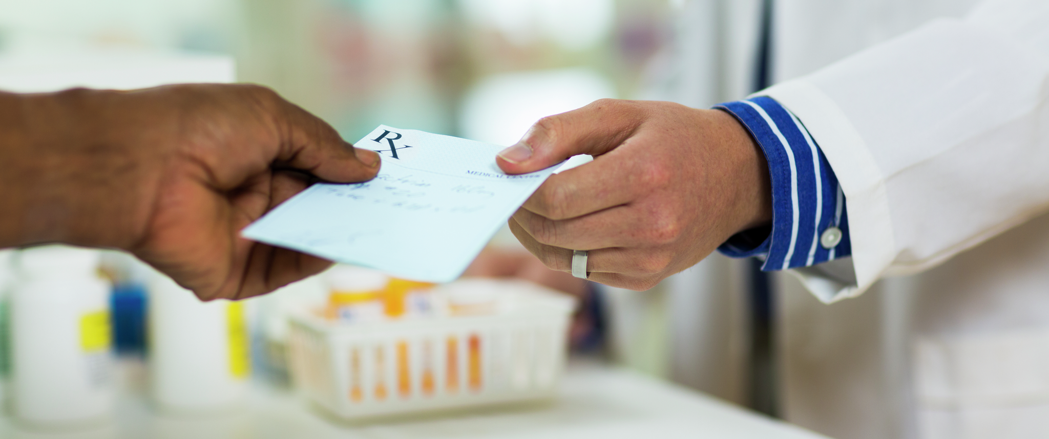A person hands a prescription to a pharmacist
