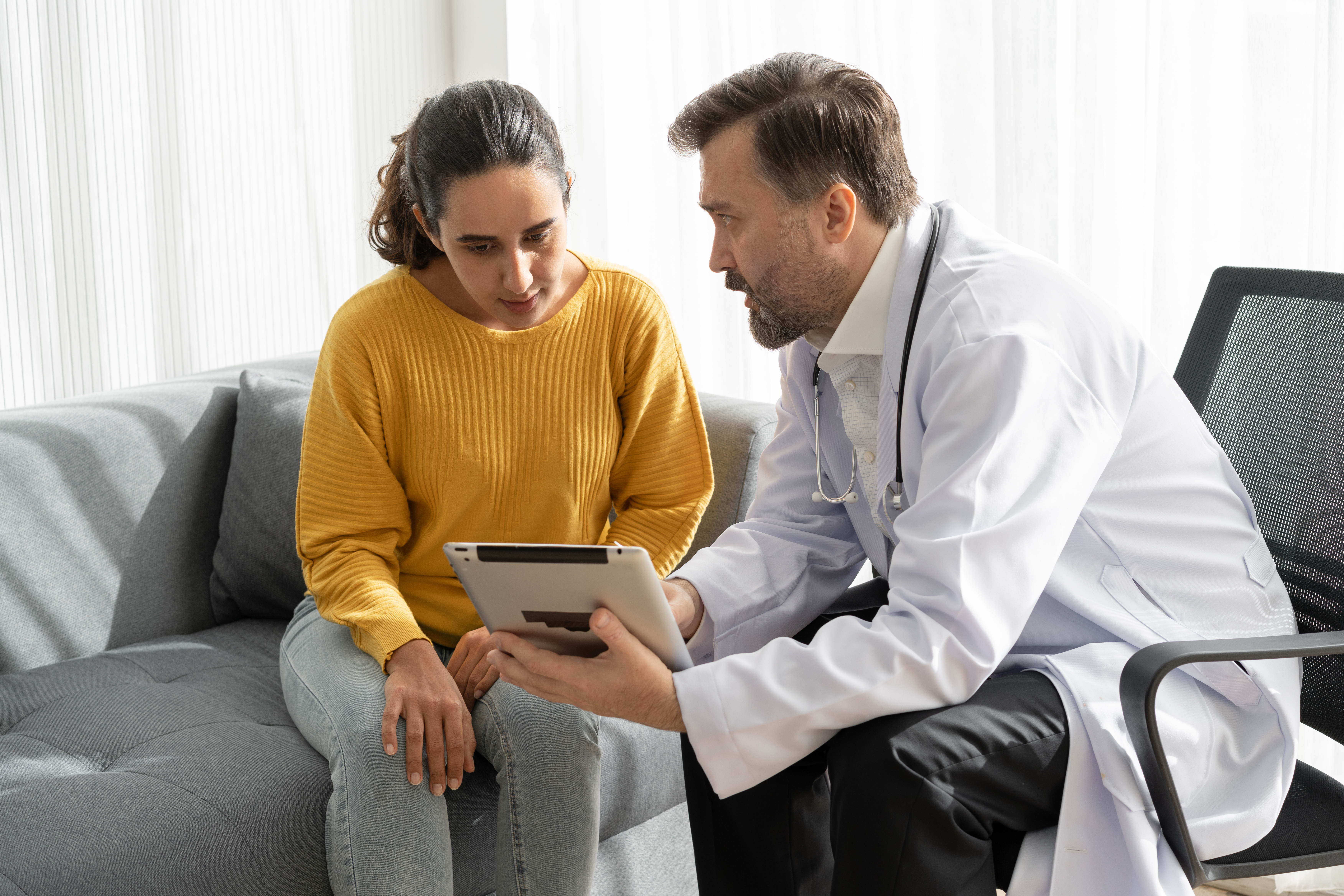 Female patient meeting with male doctor explaining medical results on tablet