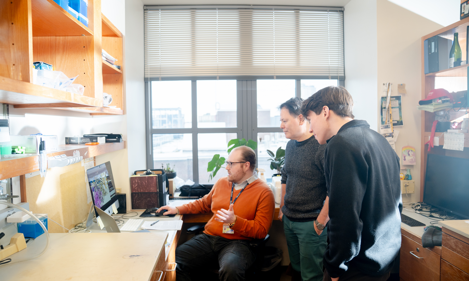 Geordan Stuckey, Roberto Dominguez, and Jonas Cook look at images on a computer screen in the lab