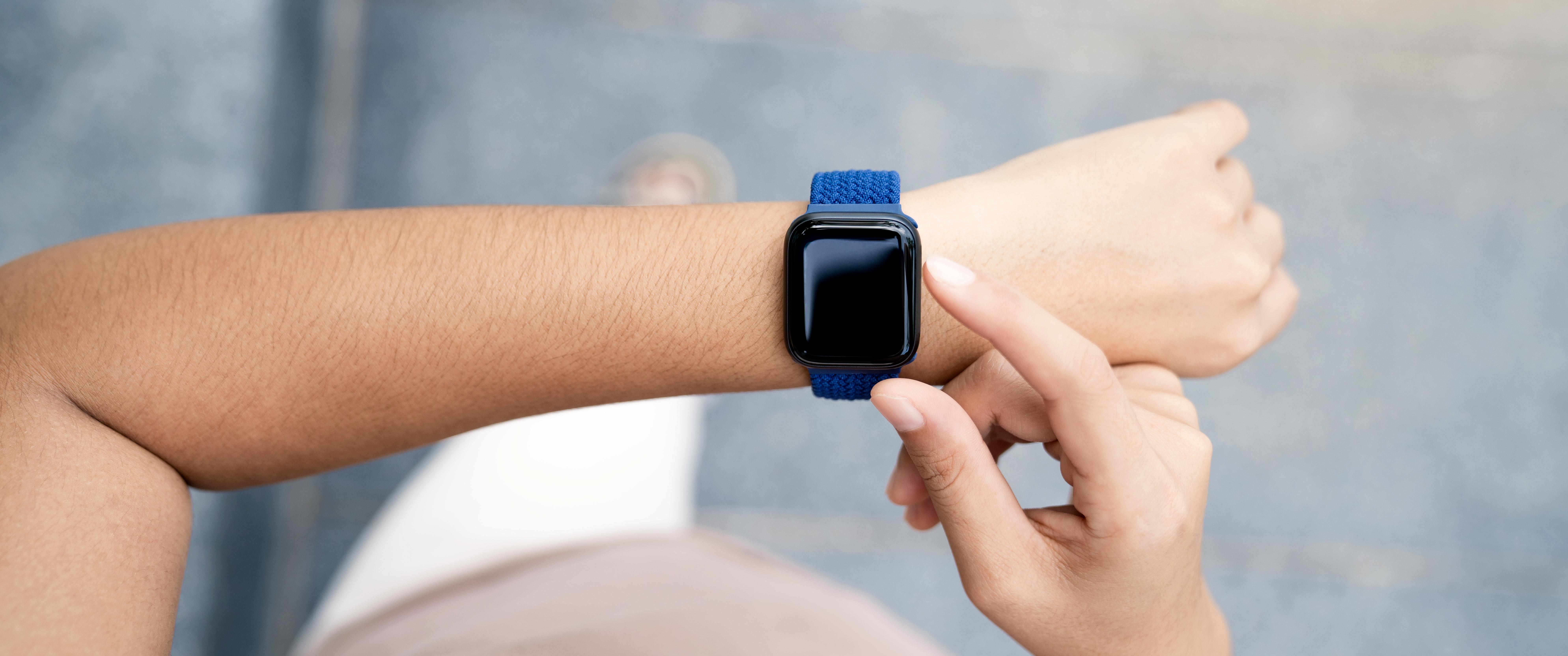 A woman holding out her arm to check her smart watch while walking.