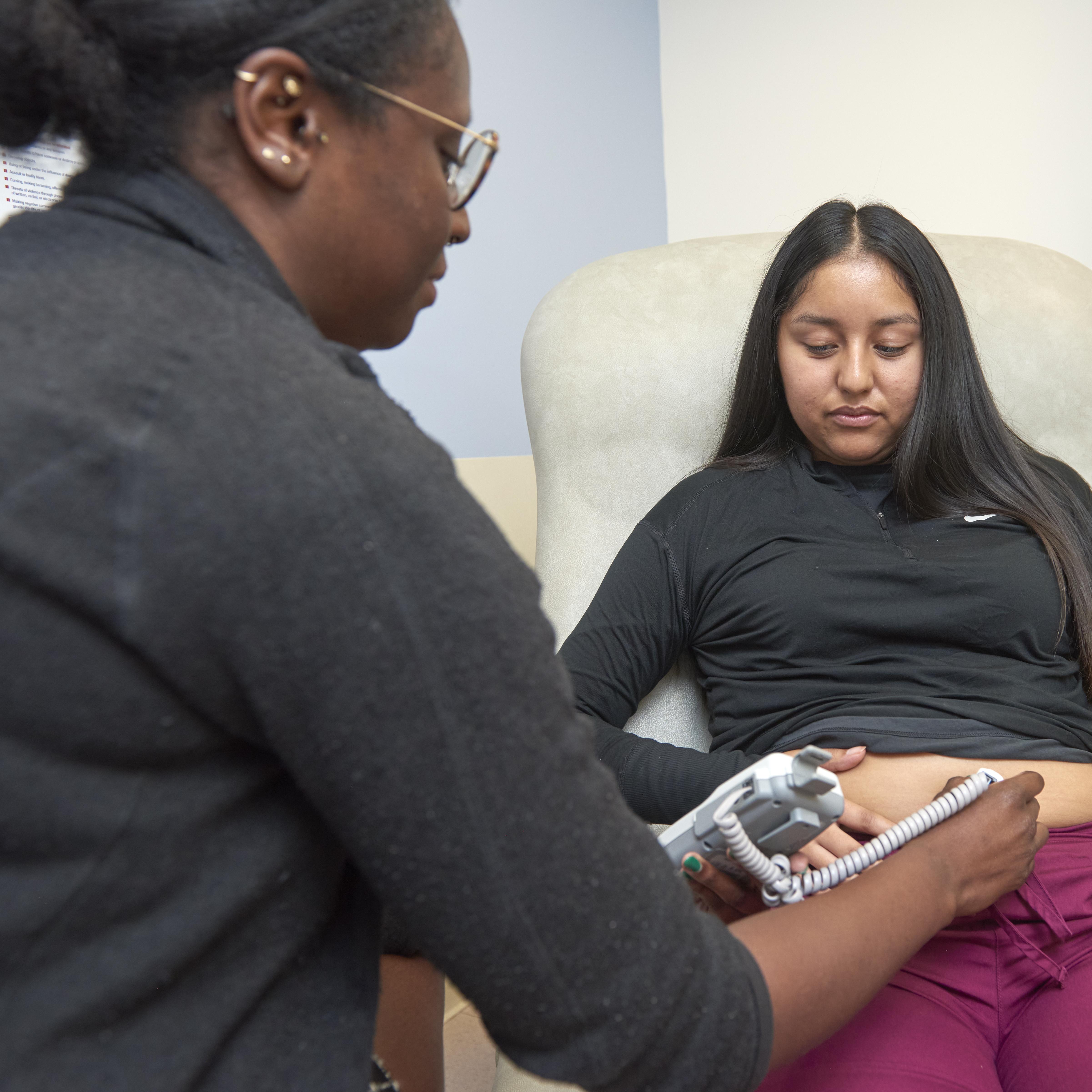 Doctor measuring the heartbeat of a developing embryo for a pregnant patient.