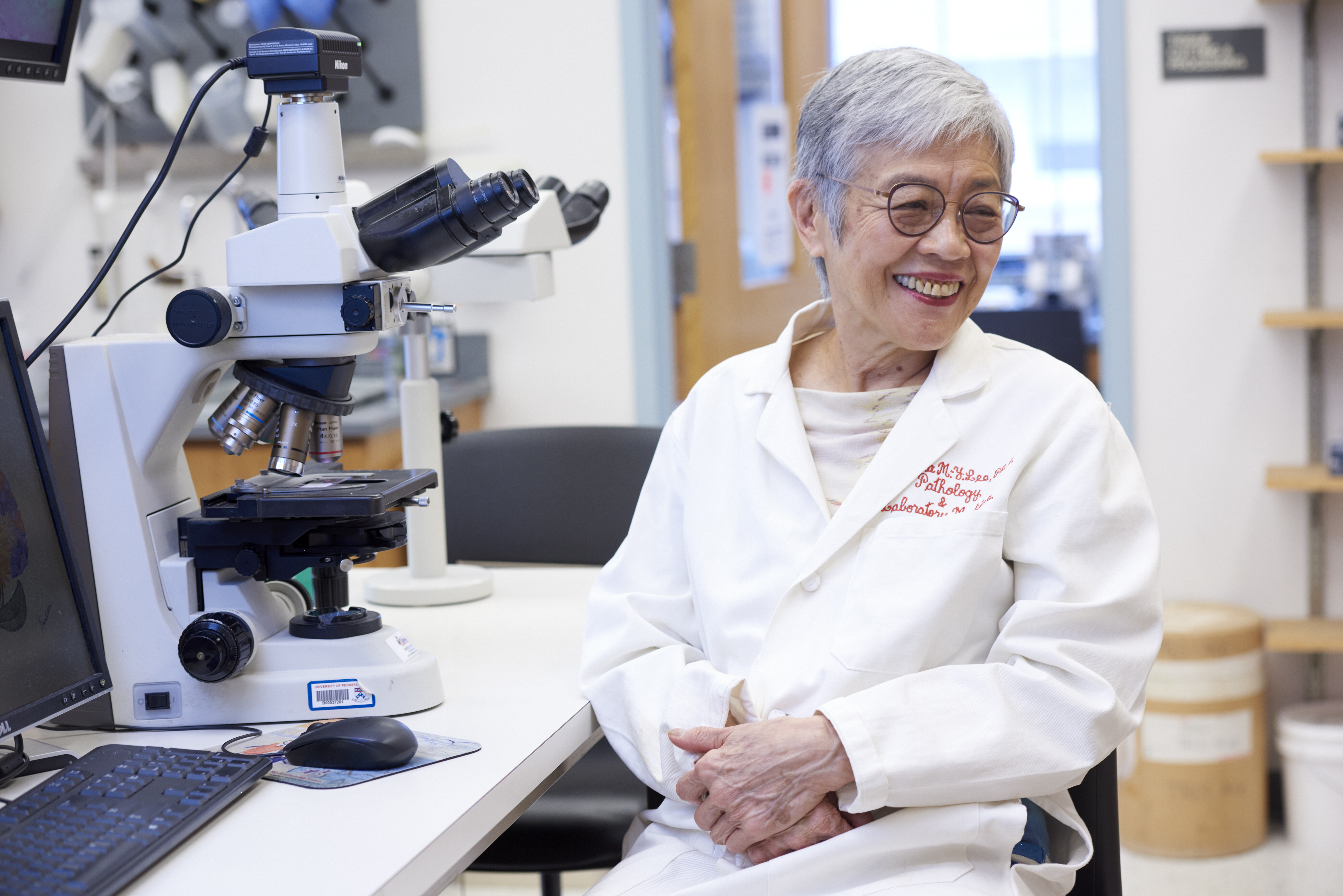 Virginia Lee in a lab coat smiles and looks off to the side