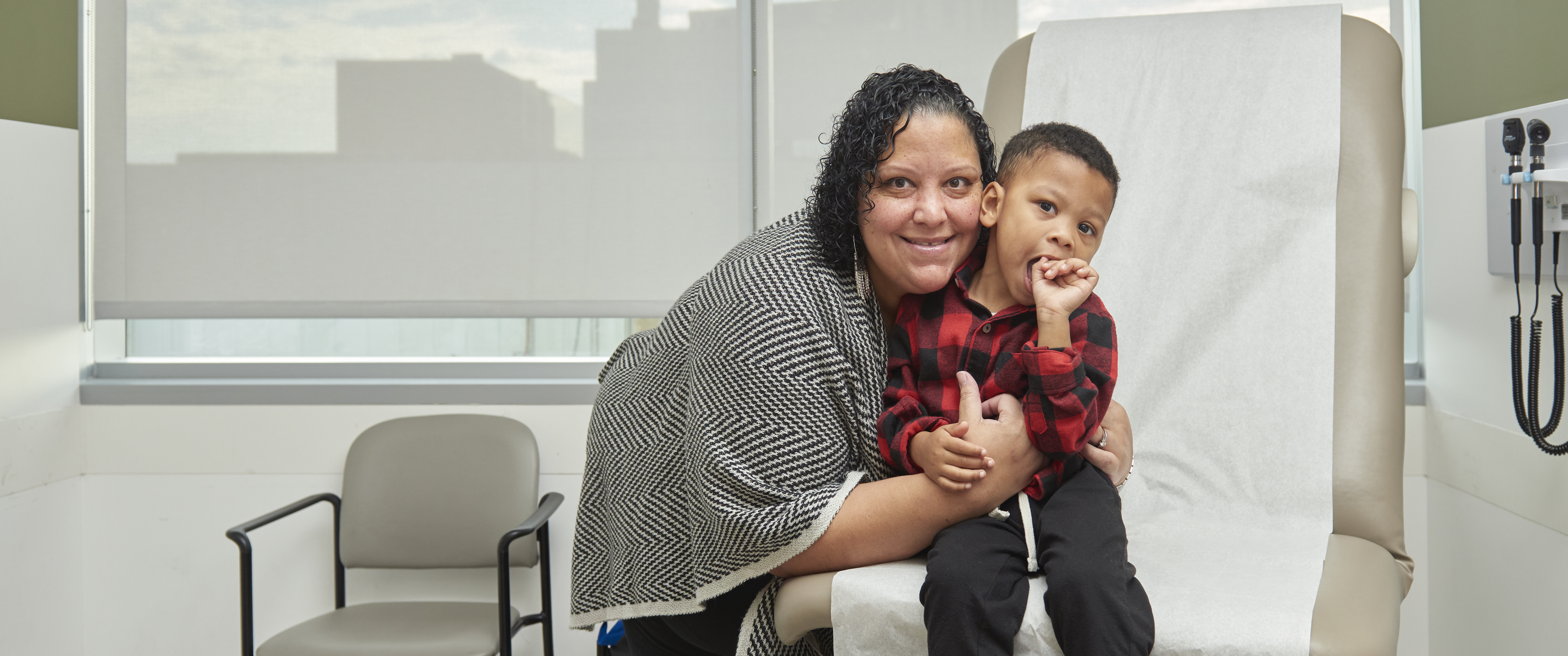 Nicole Miller snuggles her 3-year-old son Elijah in a medical office