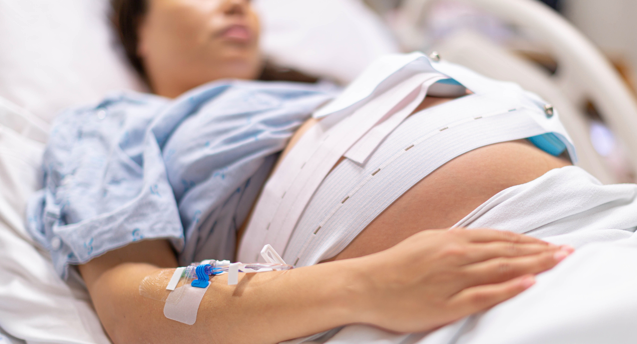 A pregnant woman in the hospital delivery room with a IV drip.