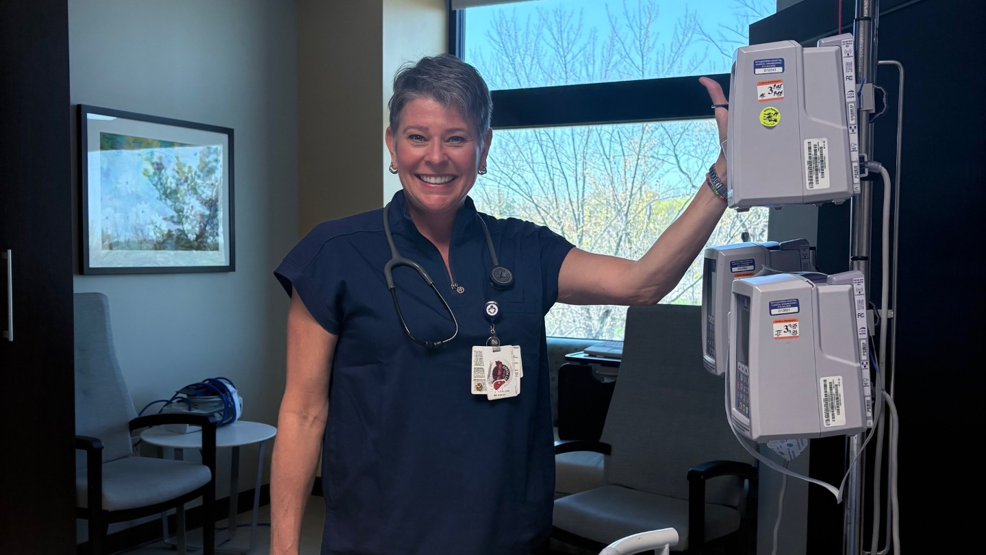 Christy Roberts smiles in a hospital room next to an IV pole
