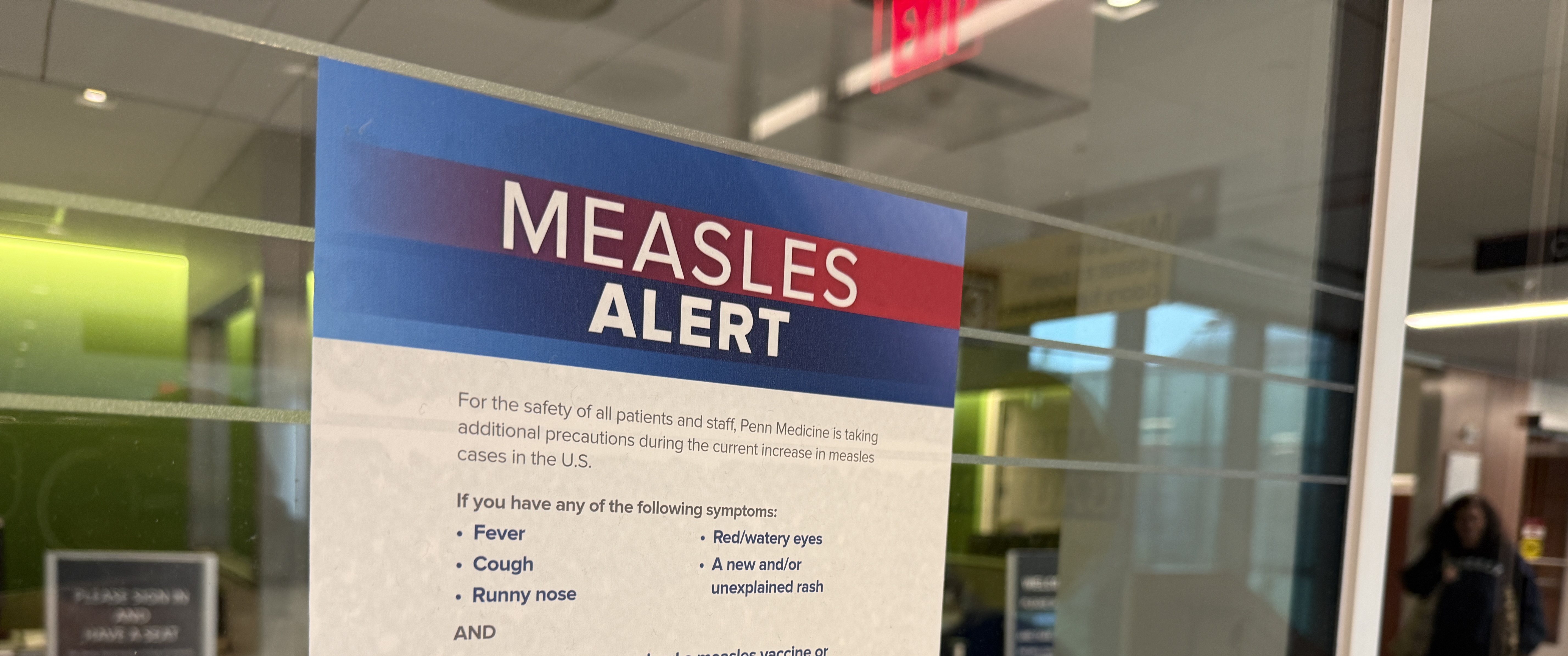 A measles-precaution sign on a glass medical facility door