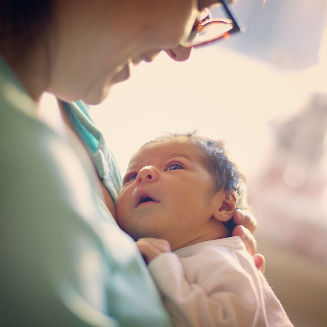 Mom smiling at newborn at hospital