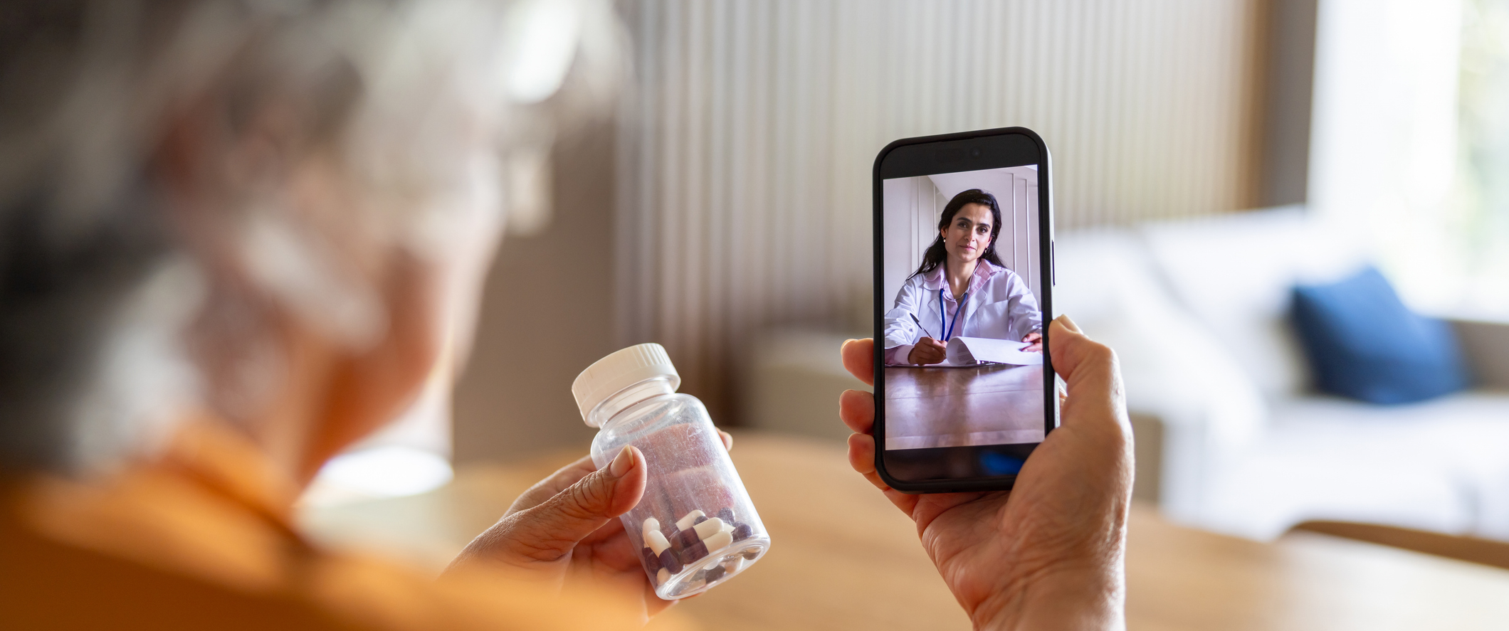 A woman talking to a doctor on a phone while holding pill bottle