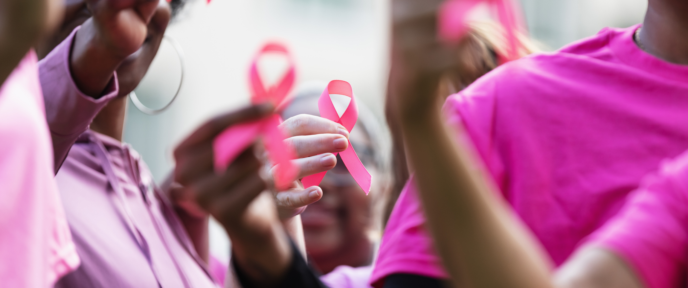 A group of women dressed in pink holding pink ribbons for breast cancer awareness.