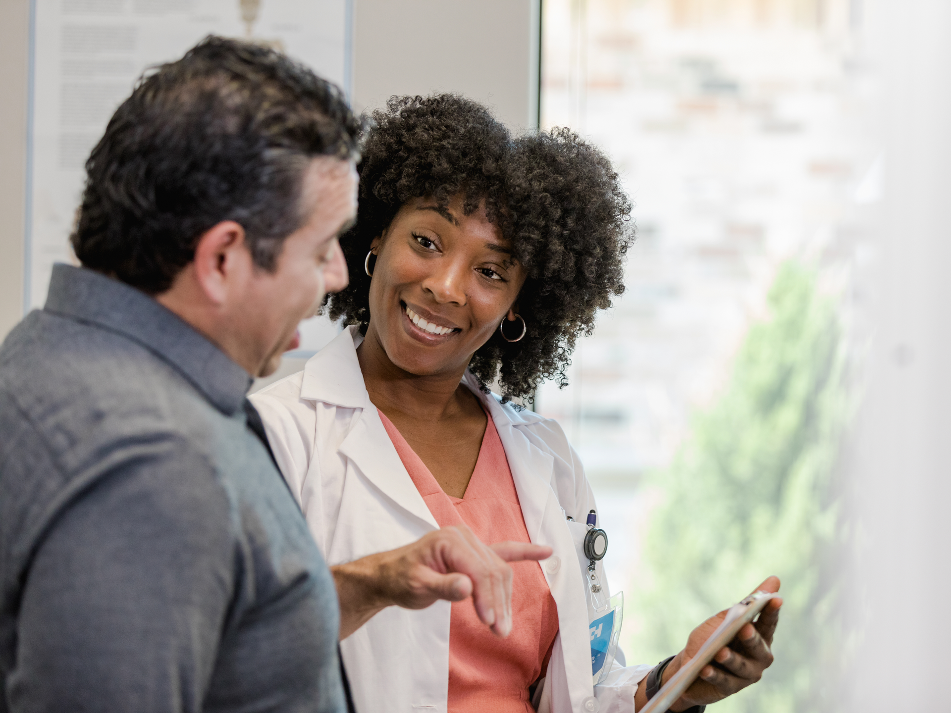 Female doctor smiles as her mature adult male patient asks questions about test results