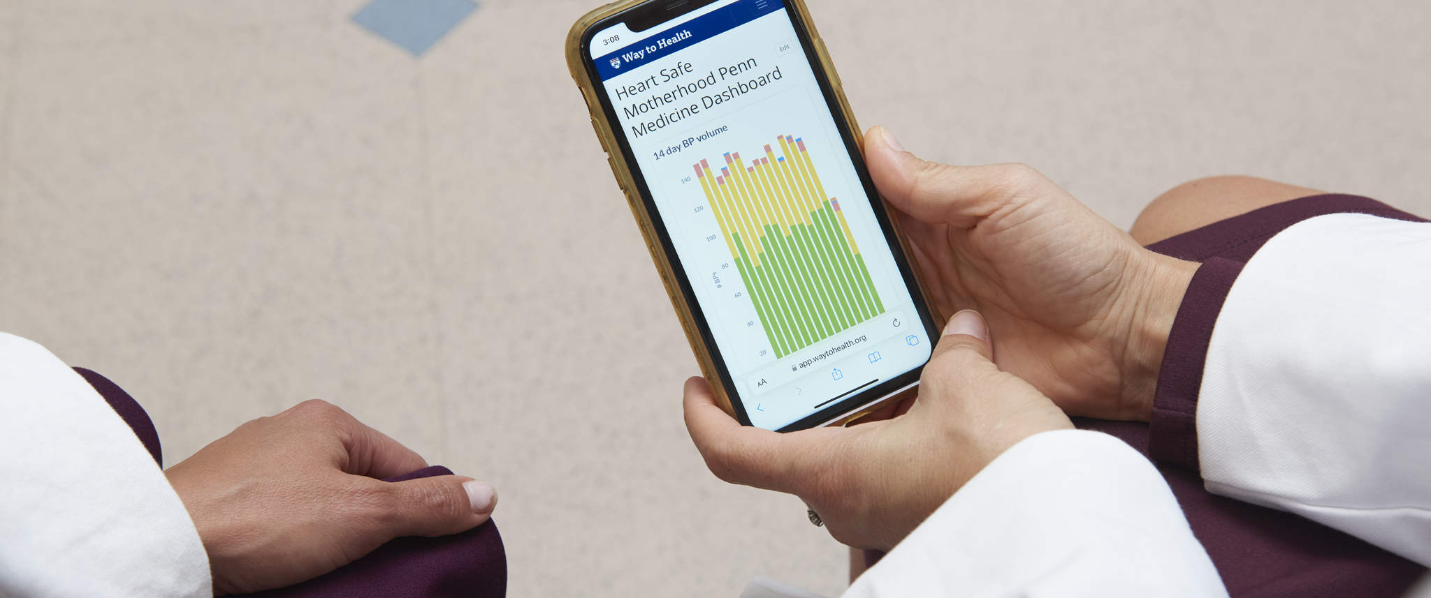 The hands of two female doctors in white coats hold a phone whose screen displays a data chart "Heart Safe Motherhood Dashboard"