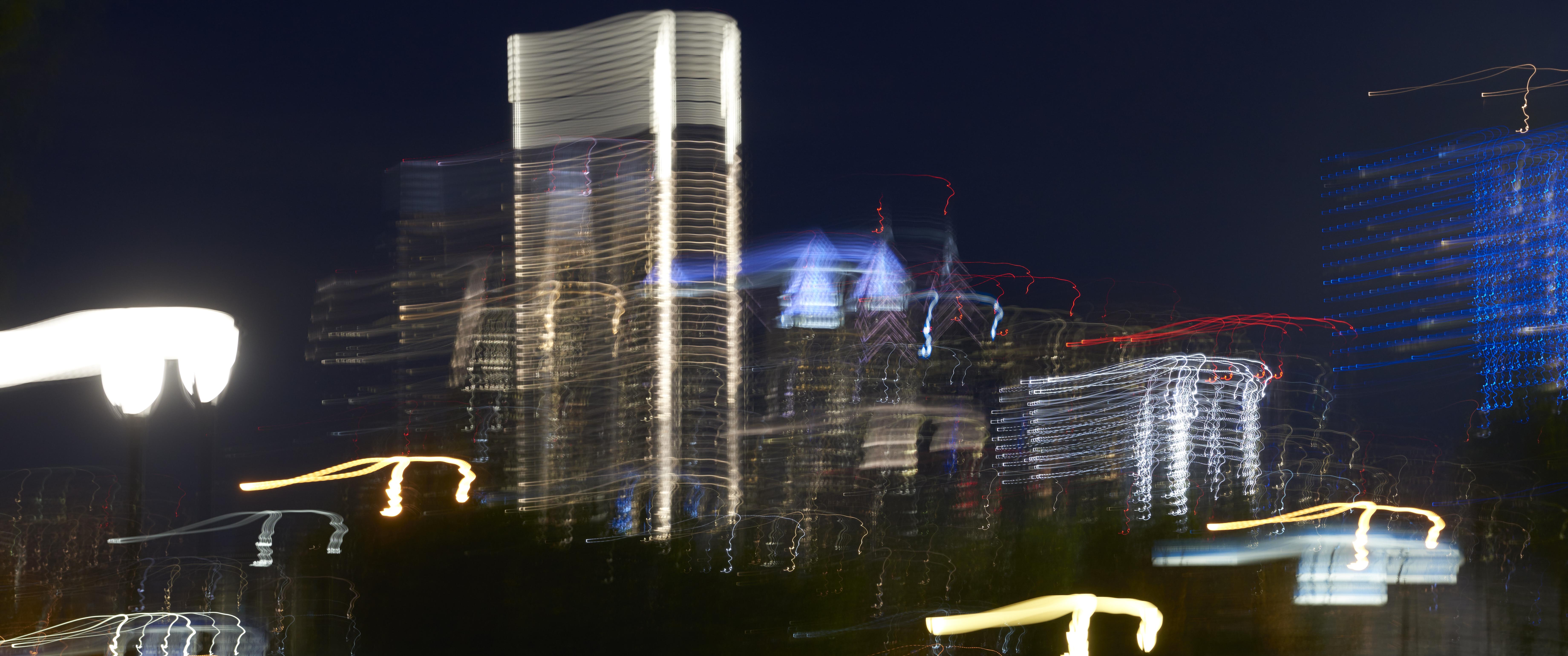 The city skyline of Philadelphia lit up at night, but distorted with a sideways motion blur