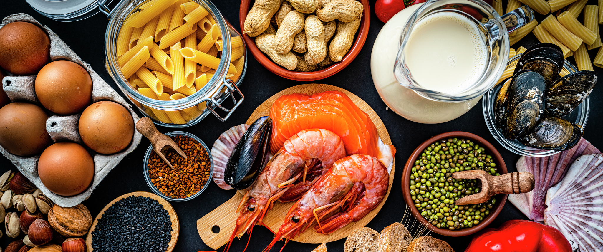A collection of common food allergens, such as dairy, nuts, gluten, and eggs, against a black background