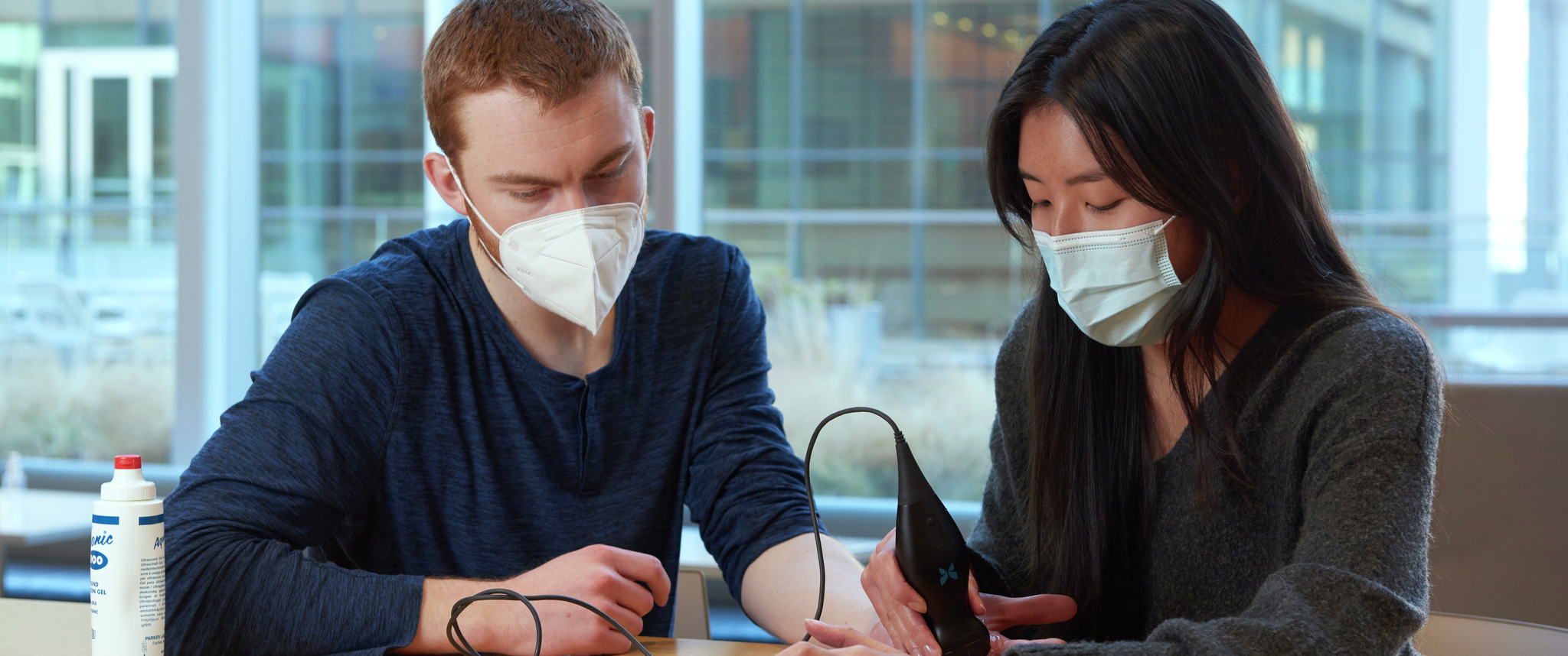 Anh Dang uses a portable ultrasound device attached to a tablet on the hand of Gavin Turner