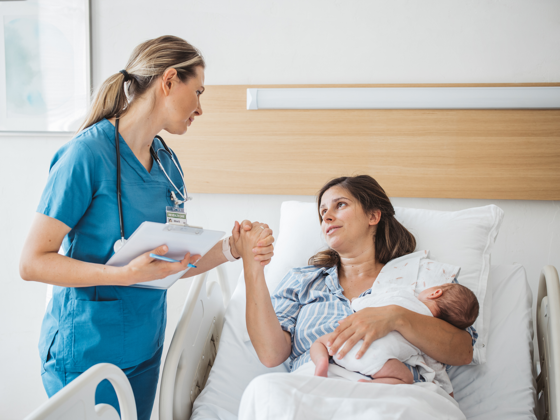 Nurse taking personal data from mother and talking to her about her mental and physical health. Mother holding newborn baby.