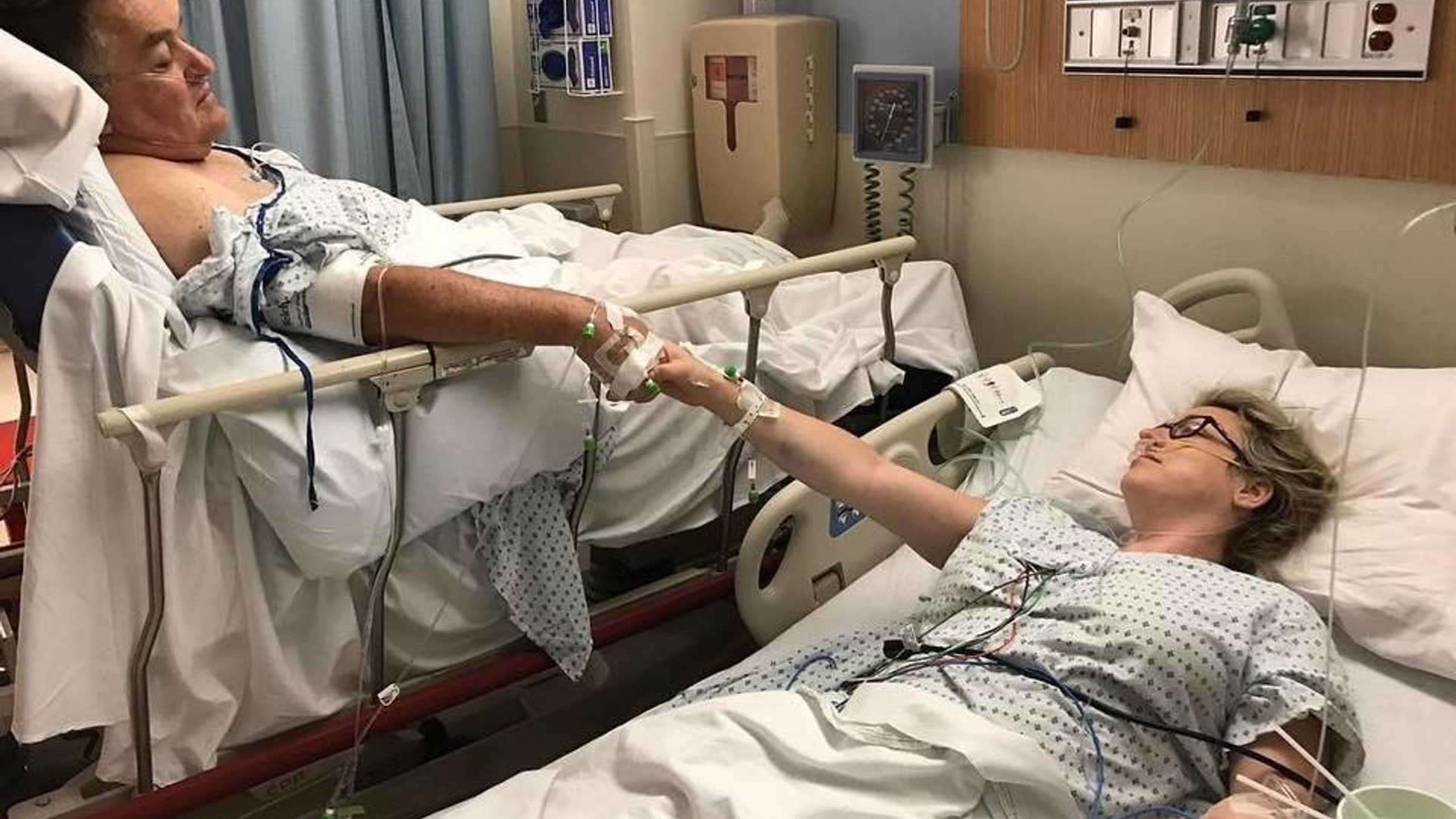 Father and daughter reach for each other in their hospital beds before living donor kidney transplant surgery