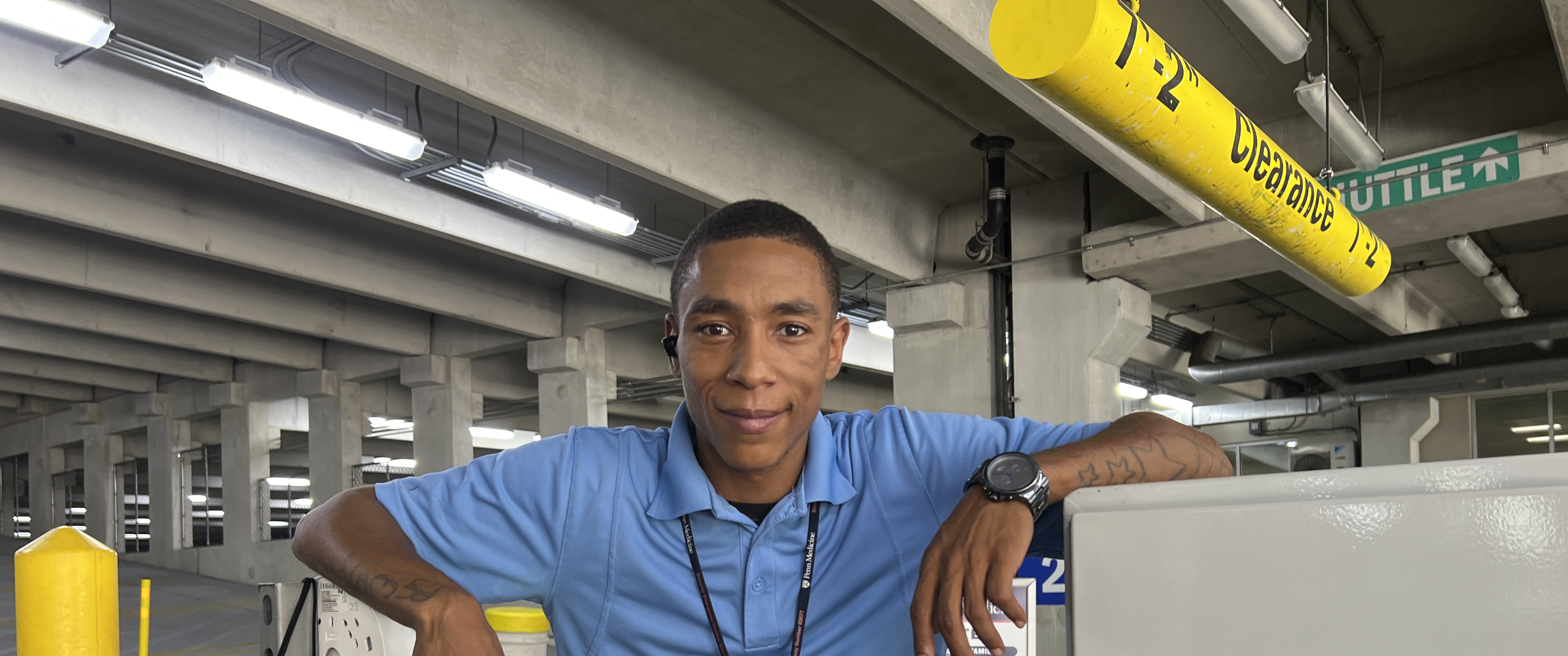Tommy Barbieri stands near the gate arm at the entrance to a parking garage, smiling