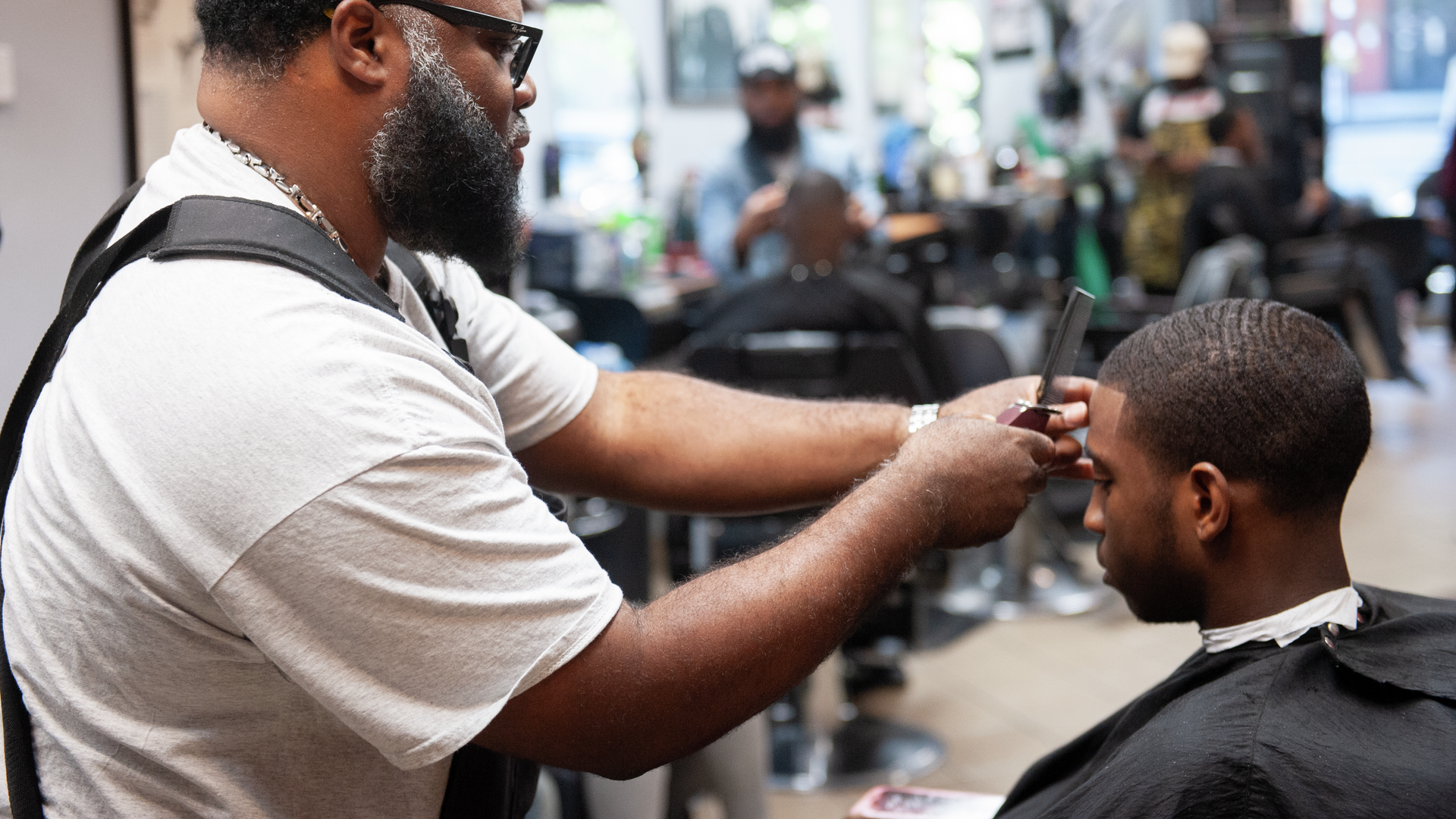 James “JB” Browne, a senior barber at Philly Cuts, trims a patron’s hair