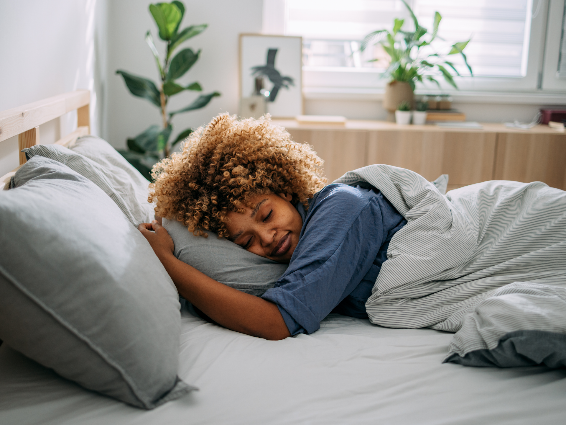 A woman sleeping on her side in bed with a content expression on her face.