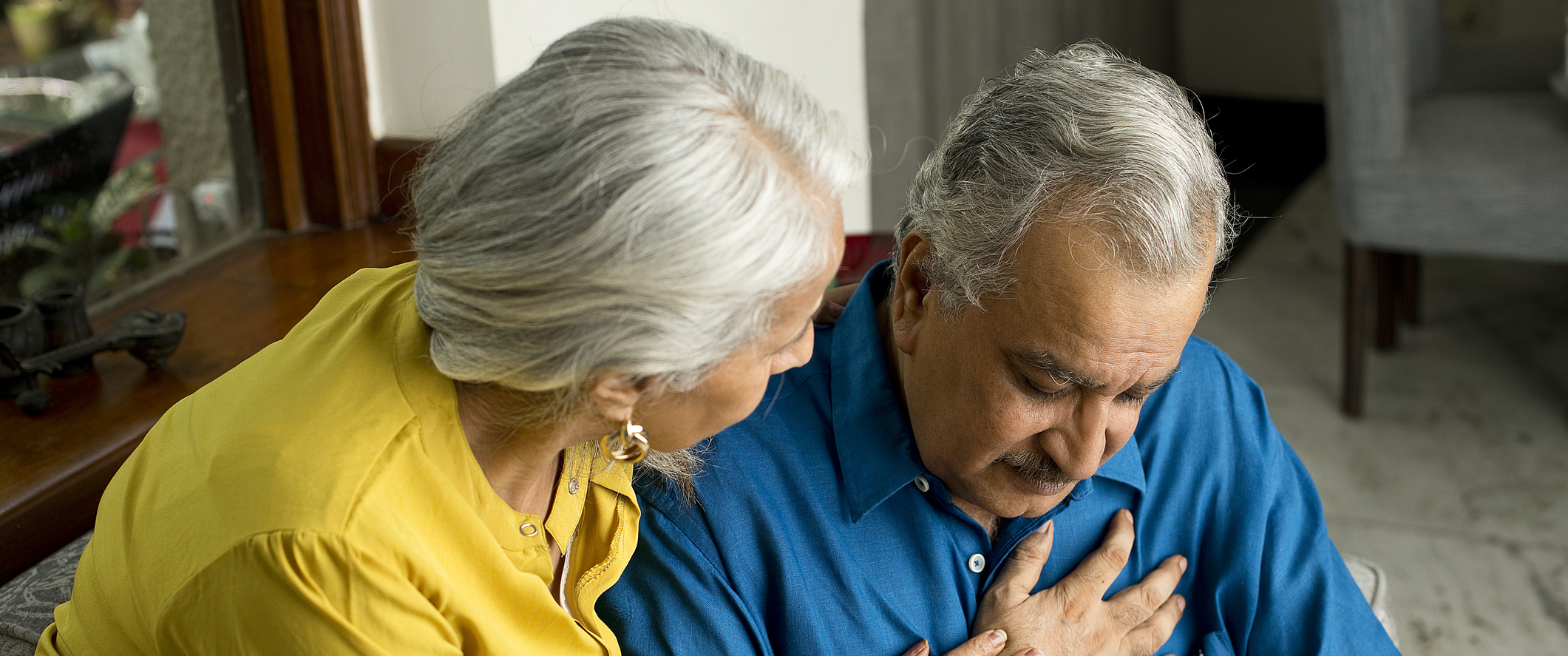 Wife comforting her husband suffering with severe chest pain