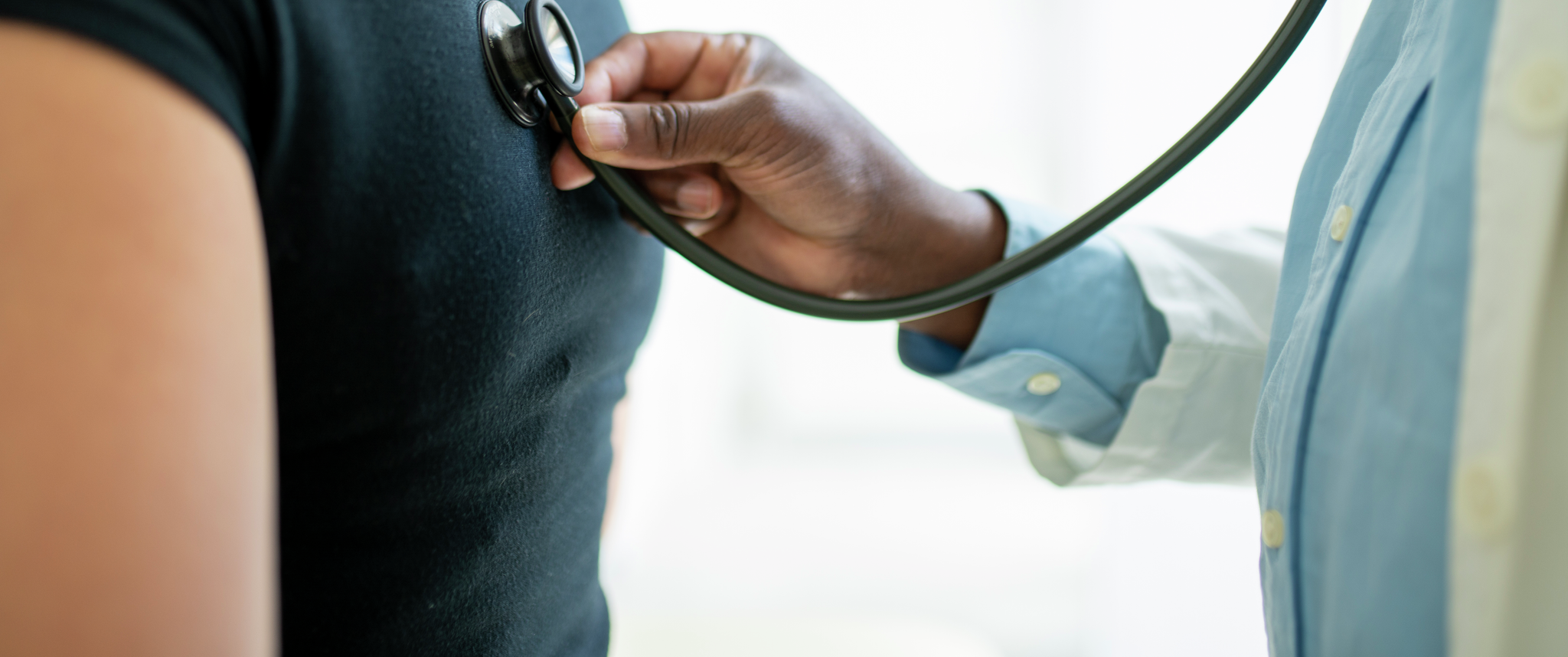 A doctor uses a stethoscope on a patient's back during a checkup 