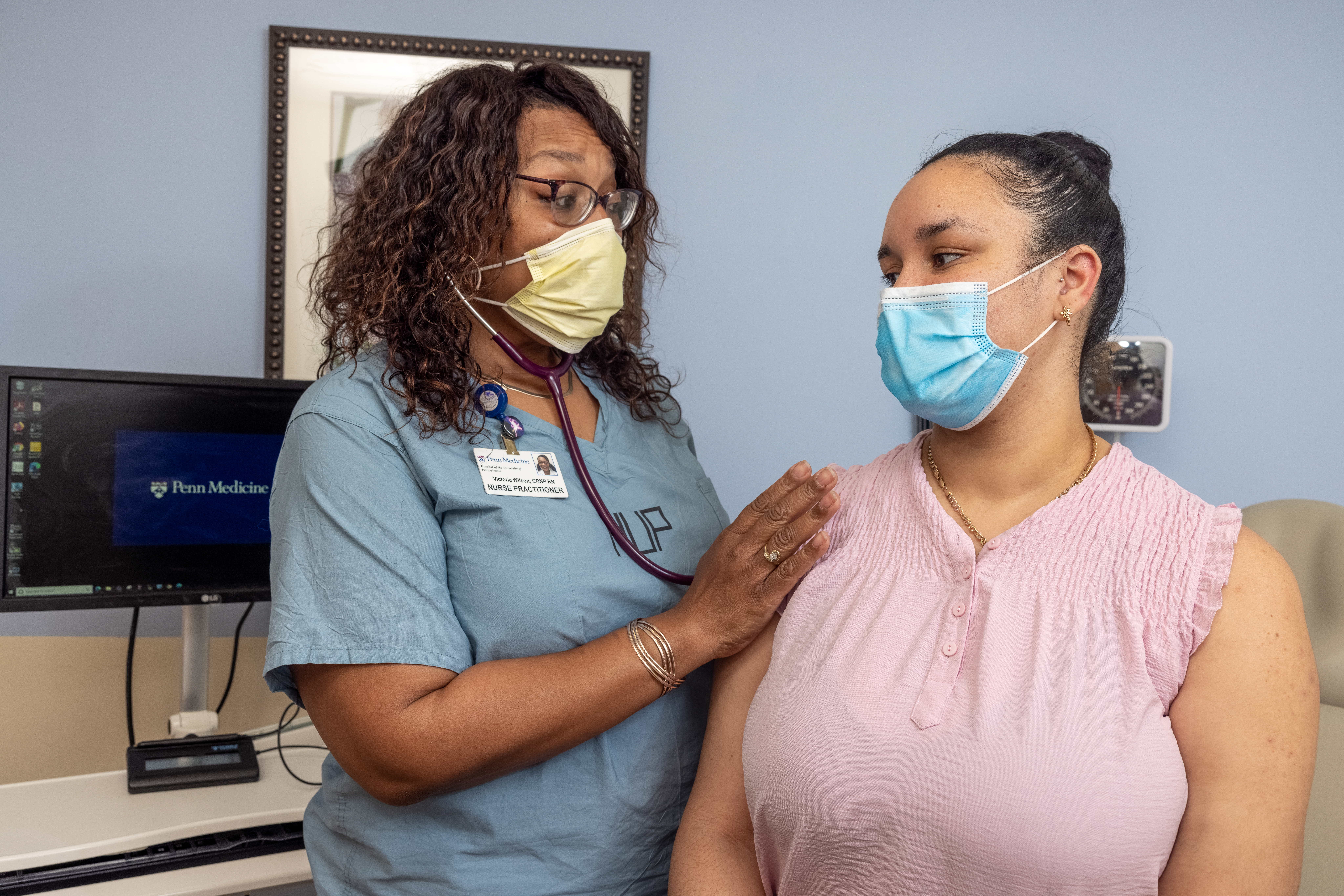 A nurse practitioner wearing HUP scrubs examines a patient