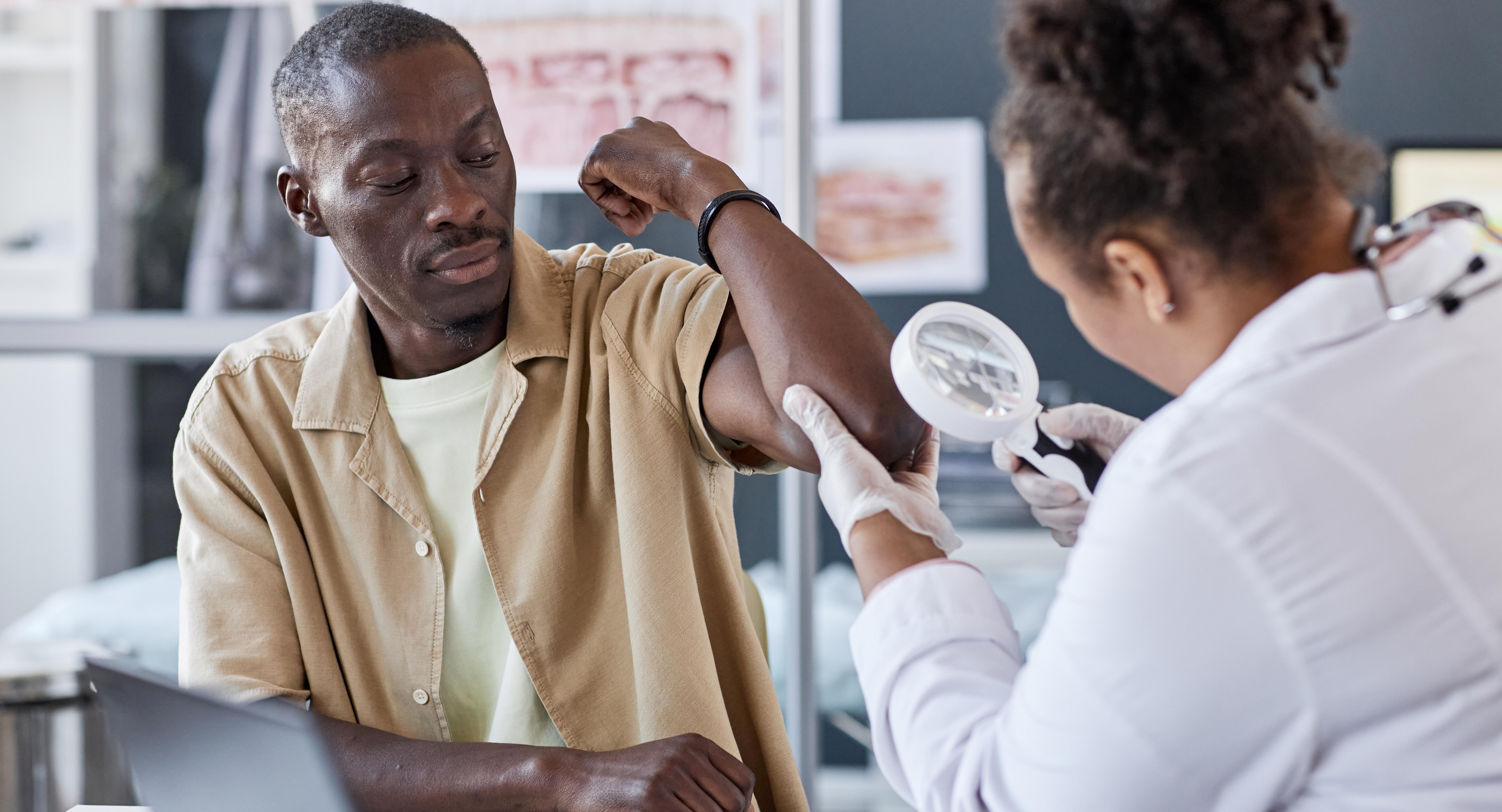 adult African American man with doctor examining skin with magnifying glass