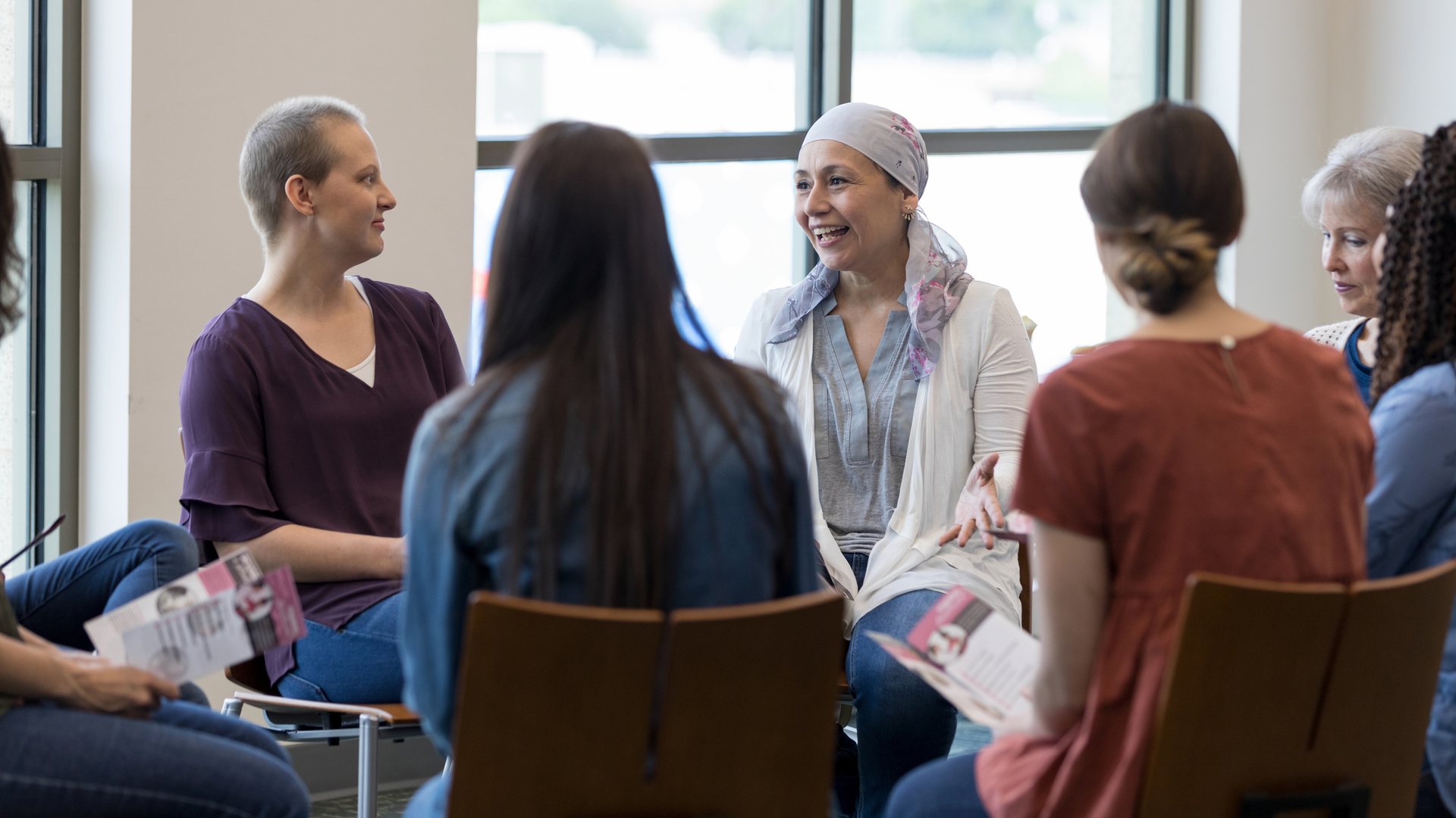 Mature woman discussing chemotherapy treatment with other women in a cancer support group.