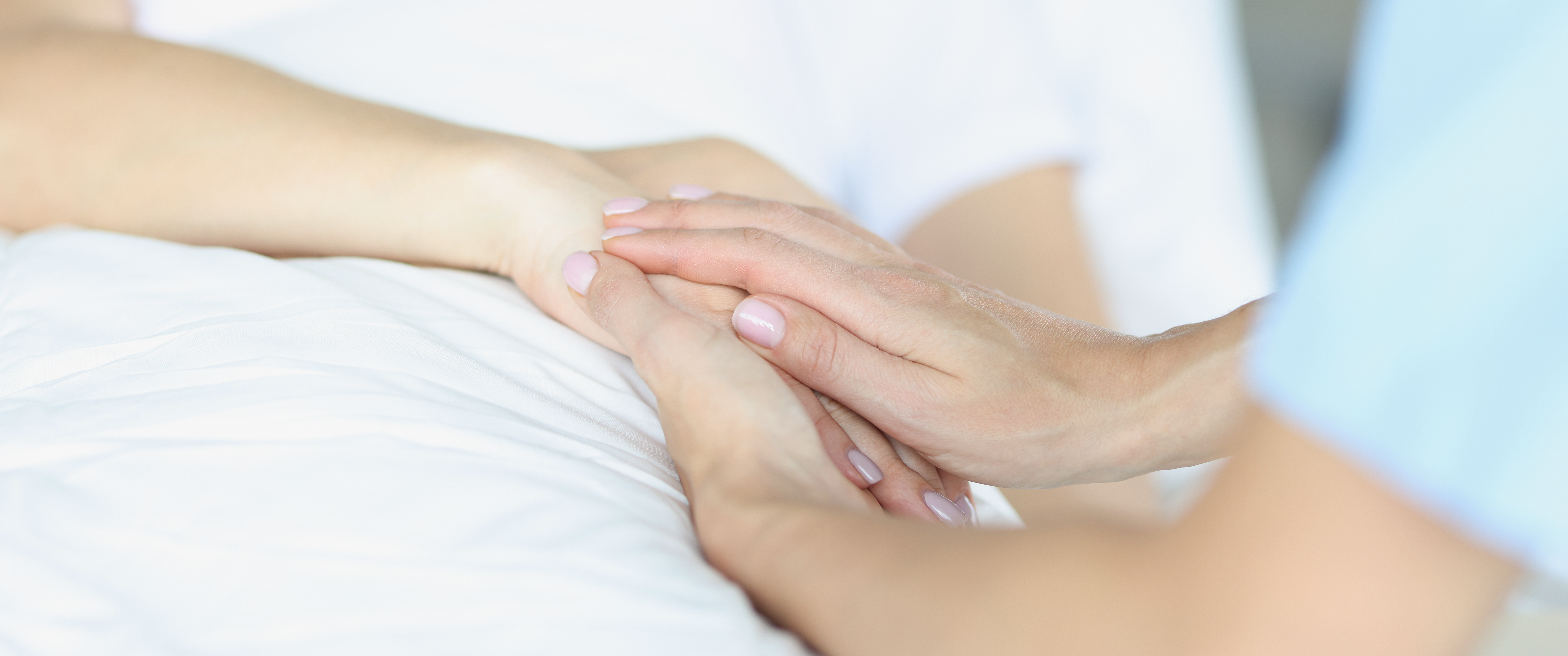 Doctor sympathetically holds hands with patient in hospital bed