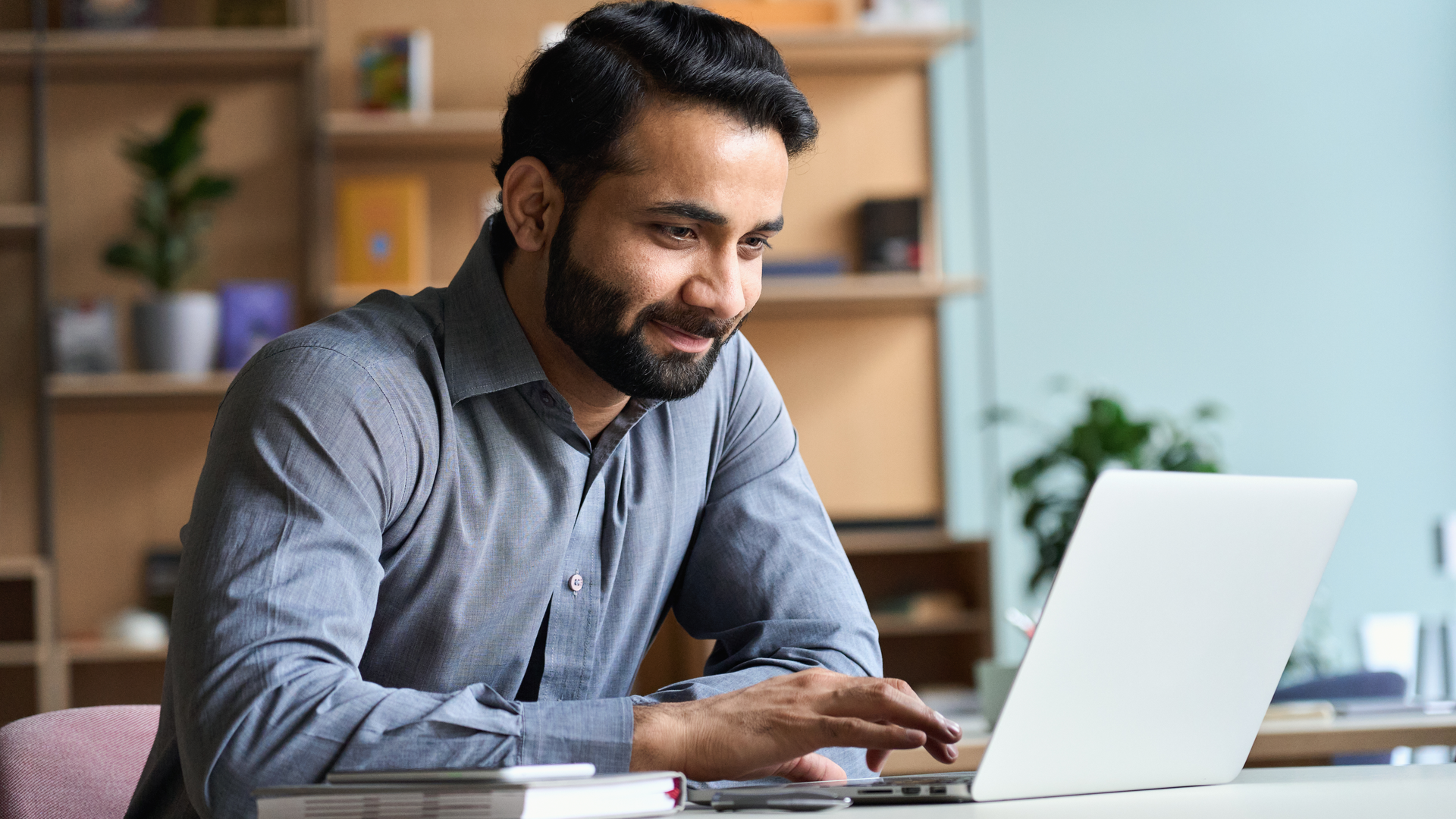 Smiling business man working on laptop at home office