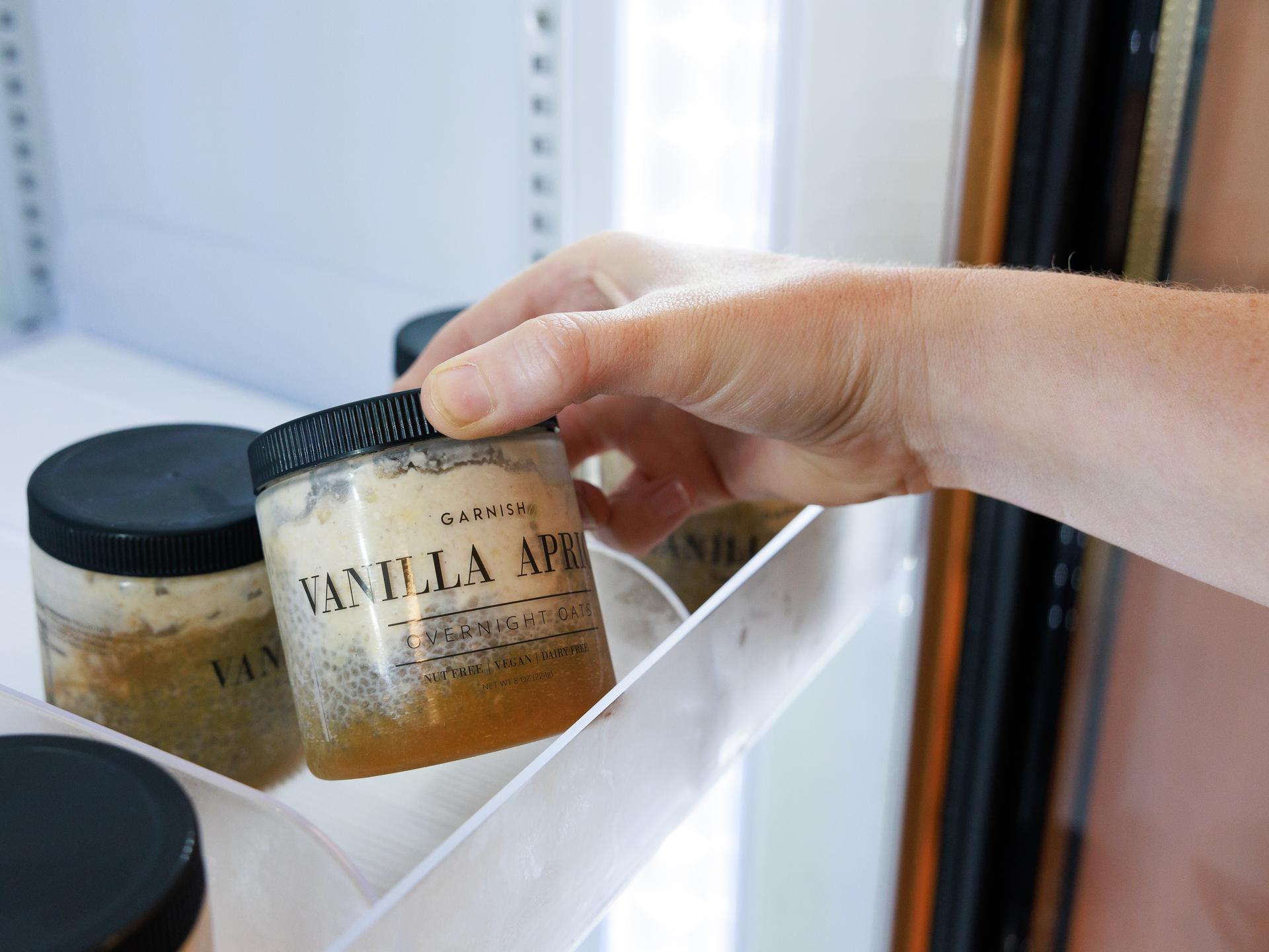 A hand reaches for a jar of overnight oats in the Community fridge