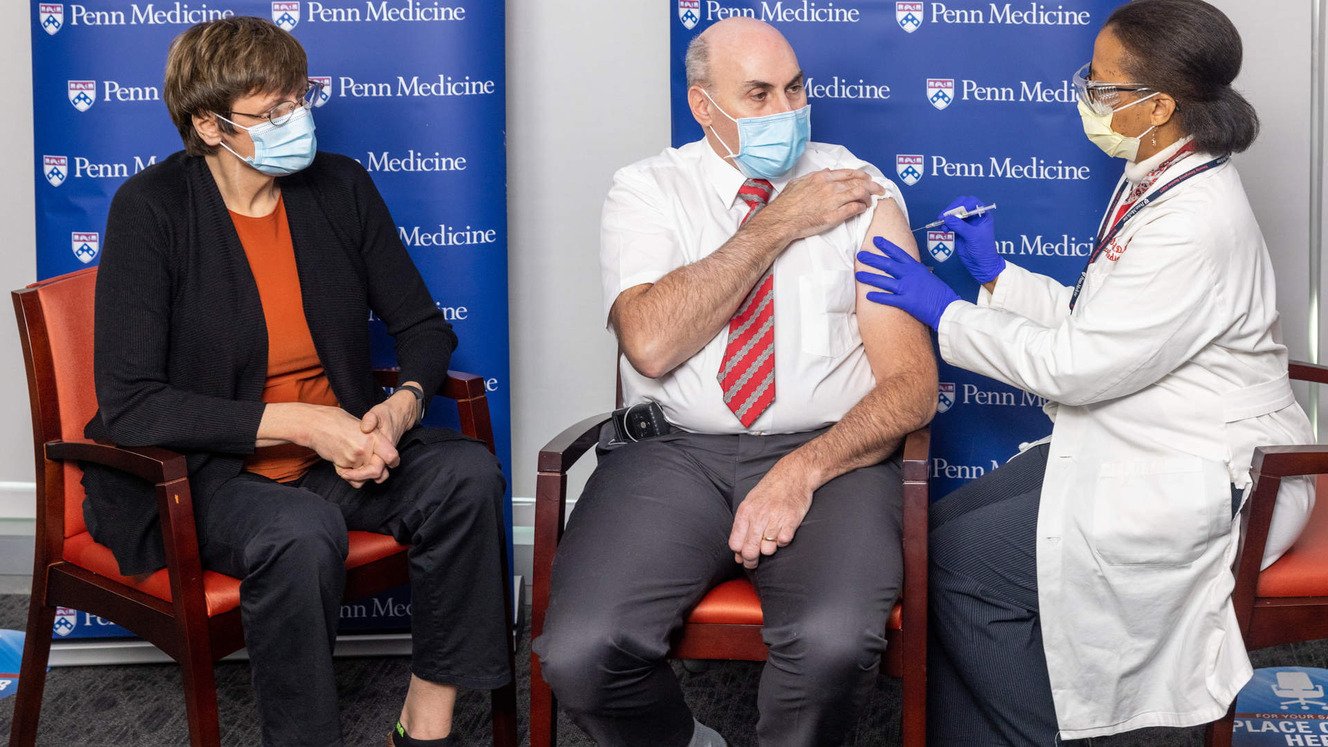 Katalin Karikó watches as a medical professional injects an mRNA vaccine for COVID-19 into Drew Weissman's upper arm