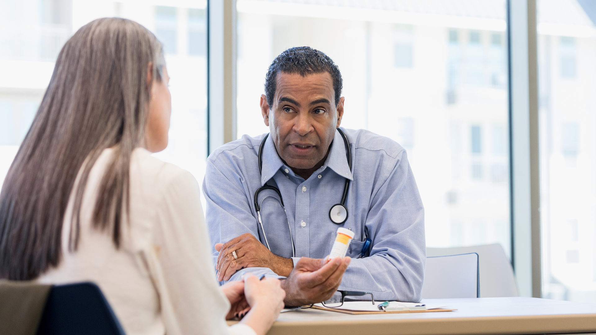 Unrecognizable woman listens to male doctor discuss drug side effects
