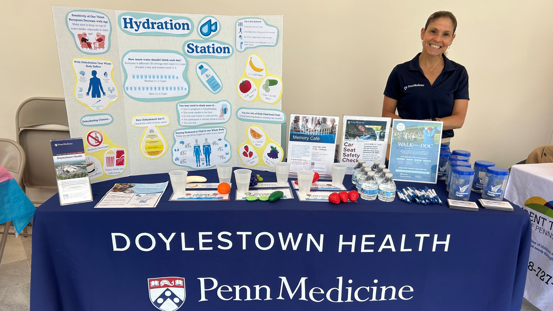 A community event information table with educator standing behind it.