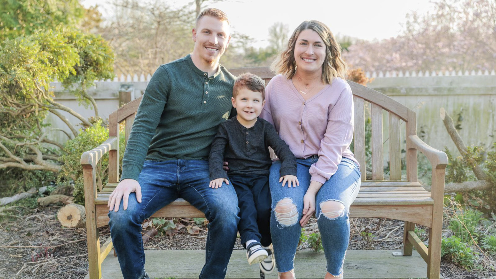 Bri Iacona sitting with her husband and son on a bench outdoors