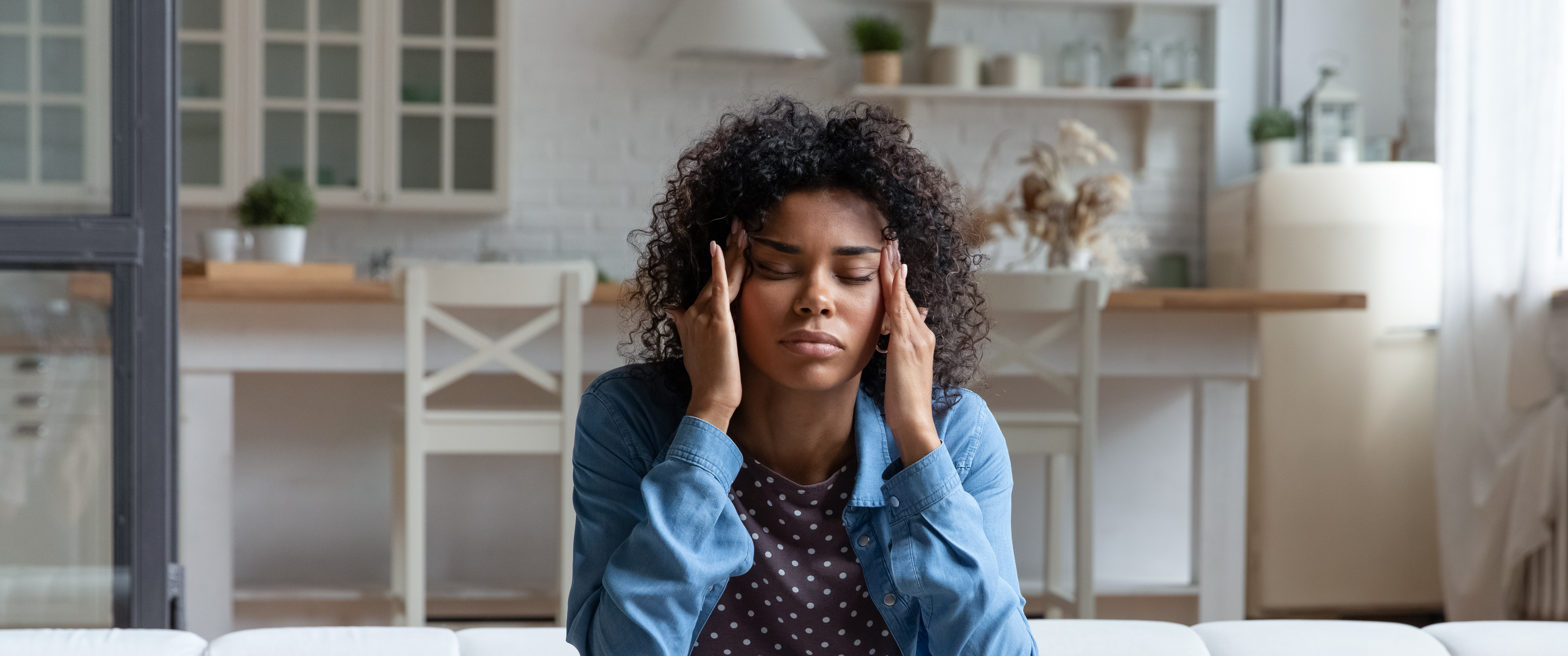 Young Black woman massaging temples, looking stressed or in pain
