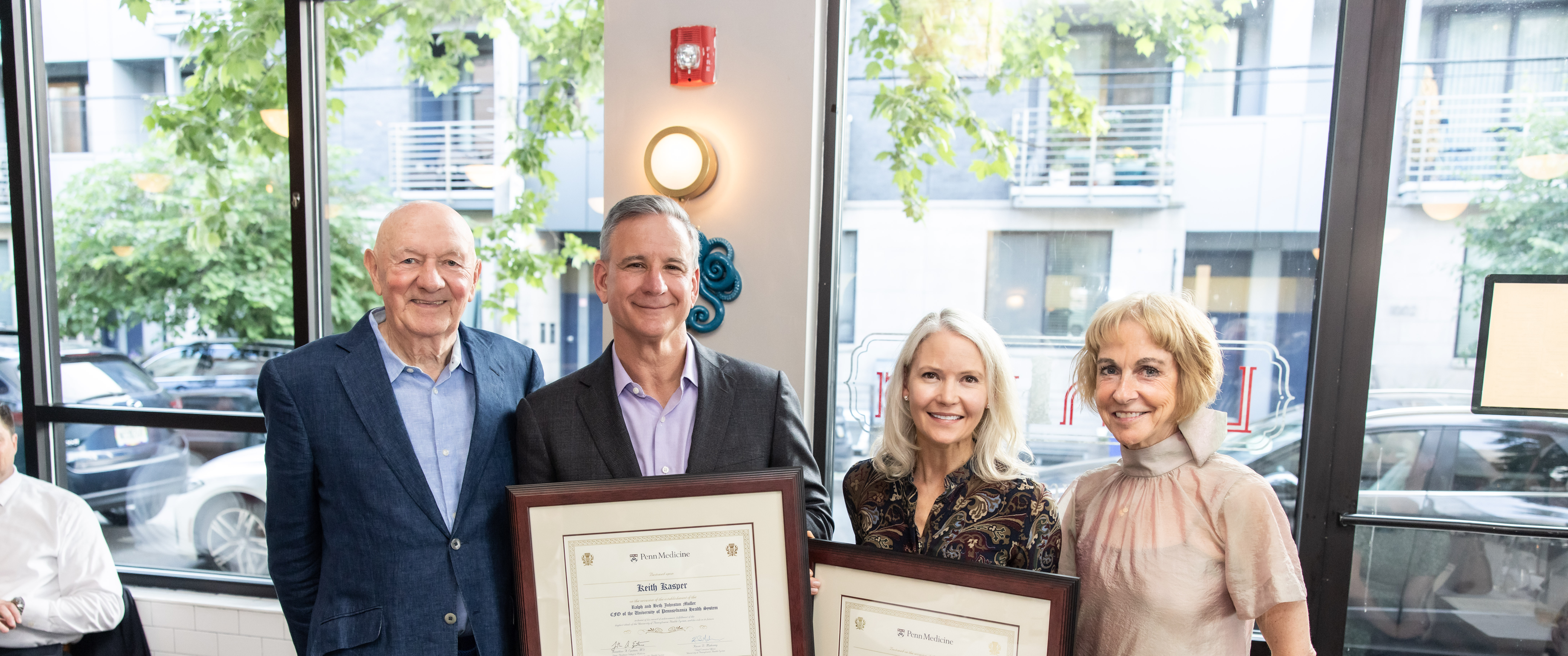 Keith Kasper and Julia Puchtler hold framed certificates recognizing them, with Ralph Muller and Beth Johnston Muller standing on either side