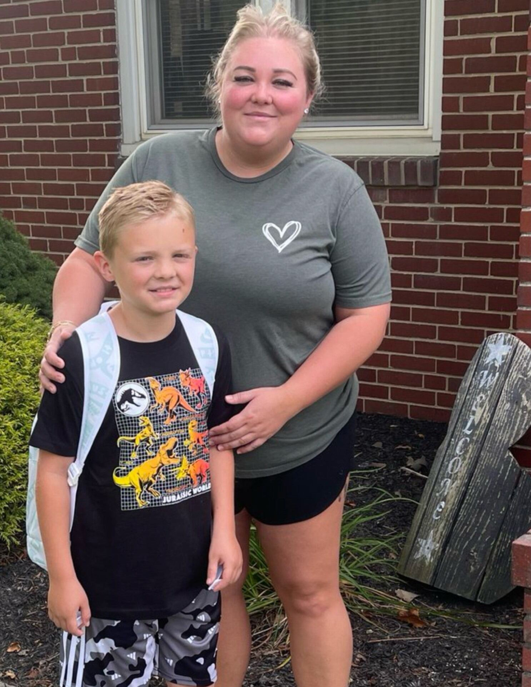 Photo of Brielle and her son, standing outside in front of a brick wall