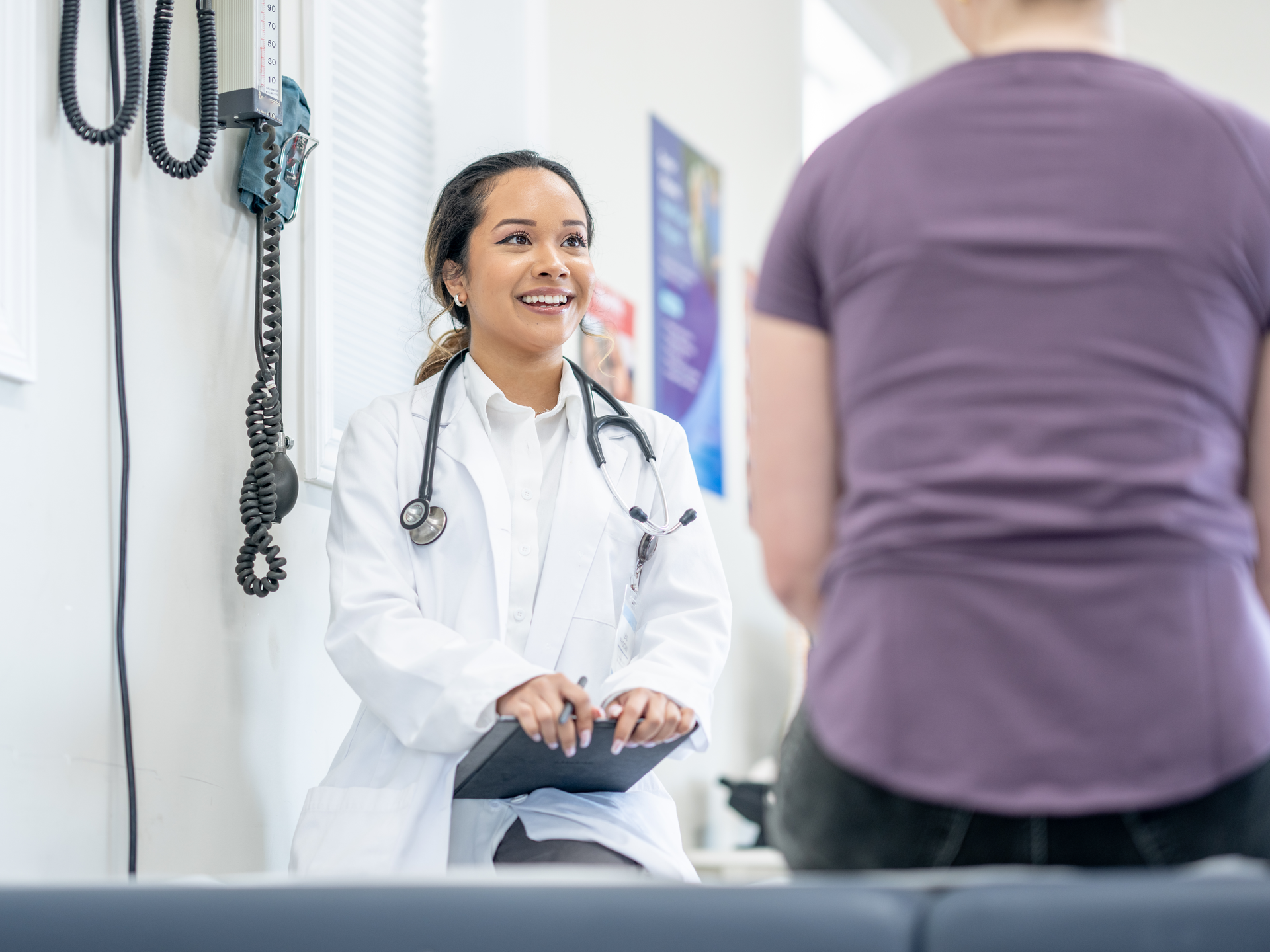  A young woman sits up on an exam table during a medical appointment with doctor
