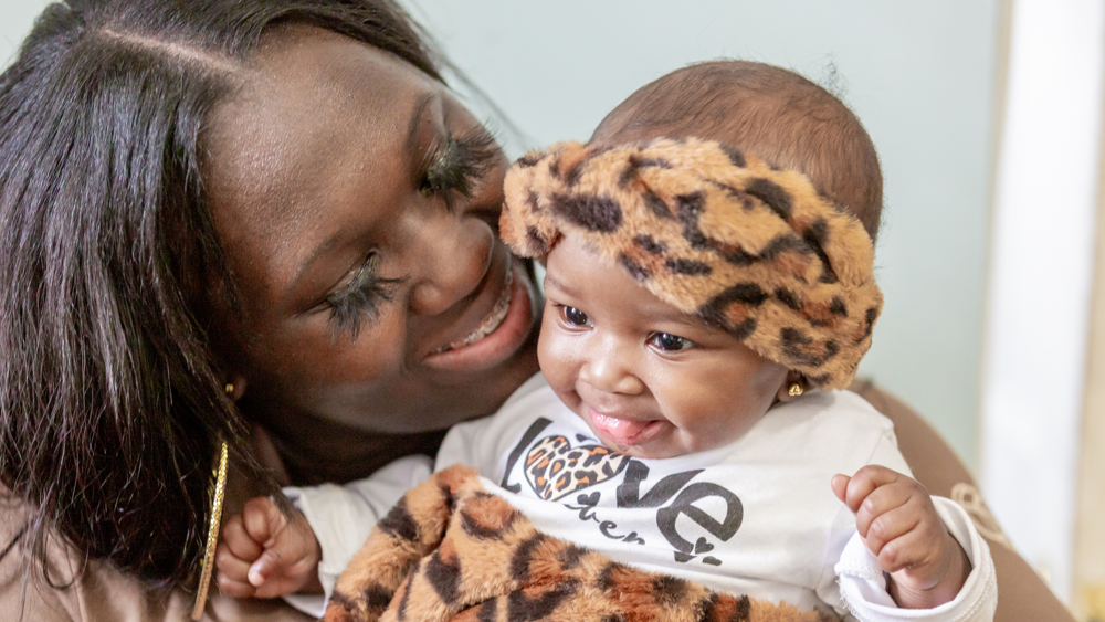 A Black woman is shown embracing her infant
