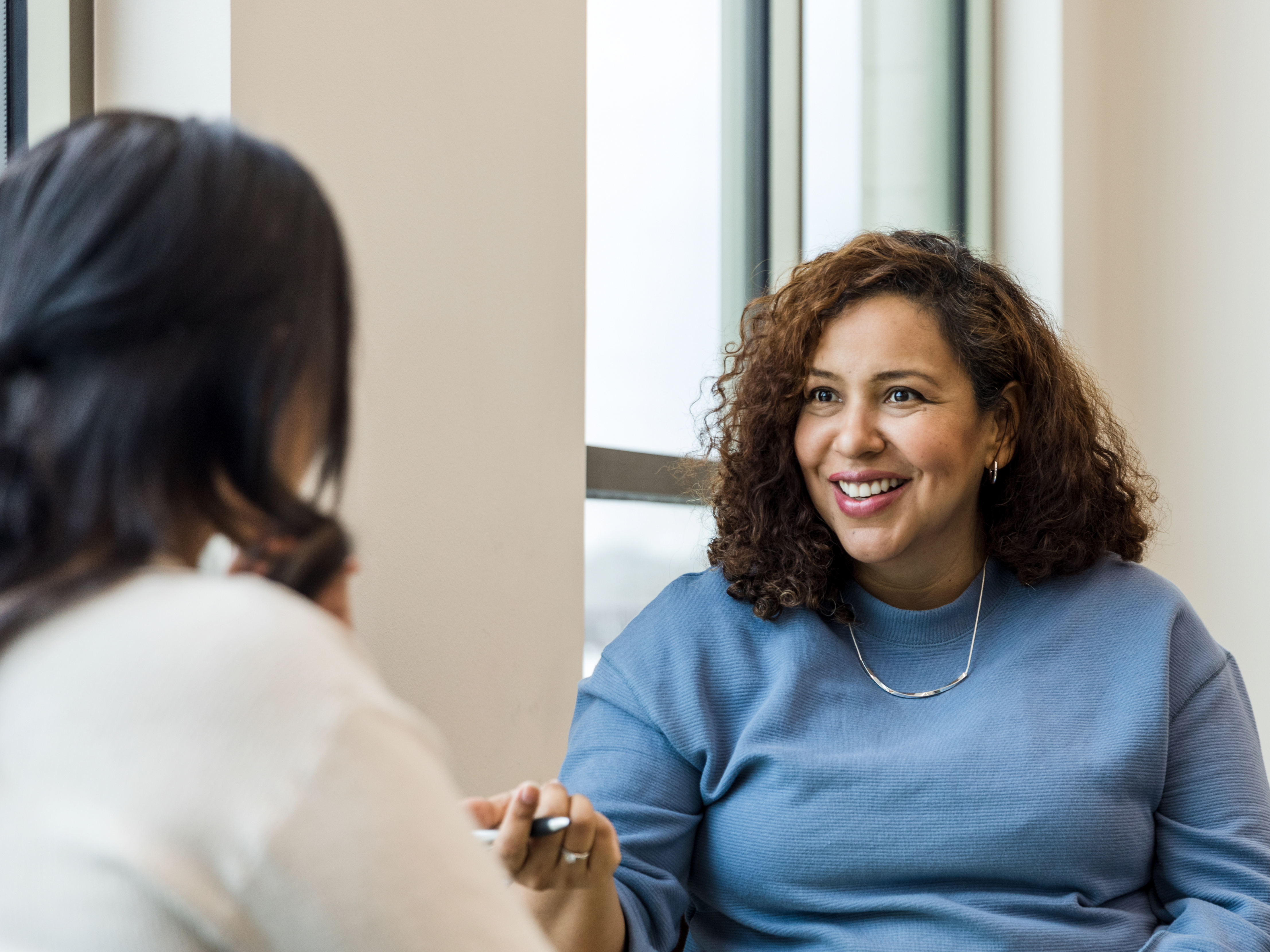 Therapist smiles and gestures to unrecognizable female patient