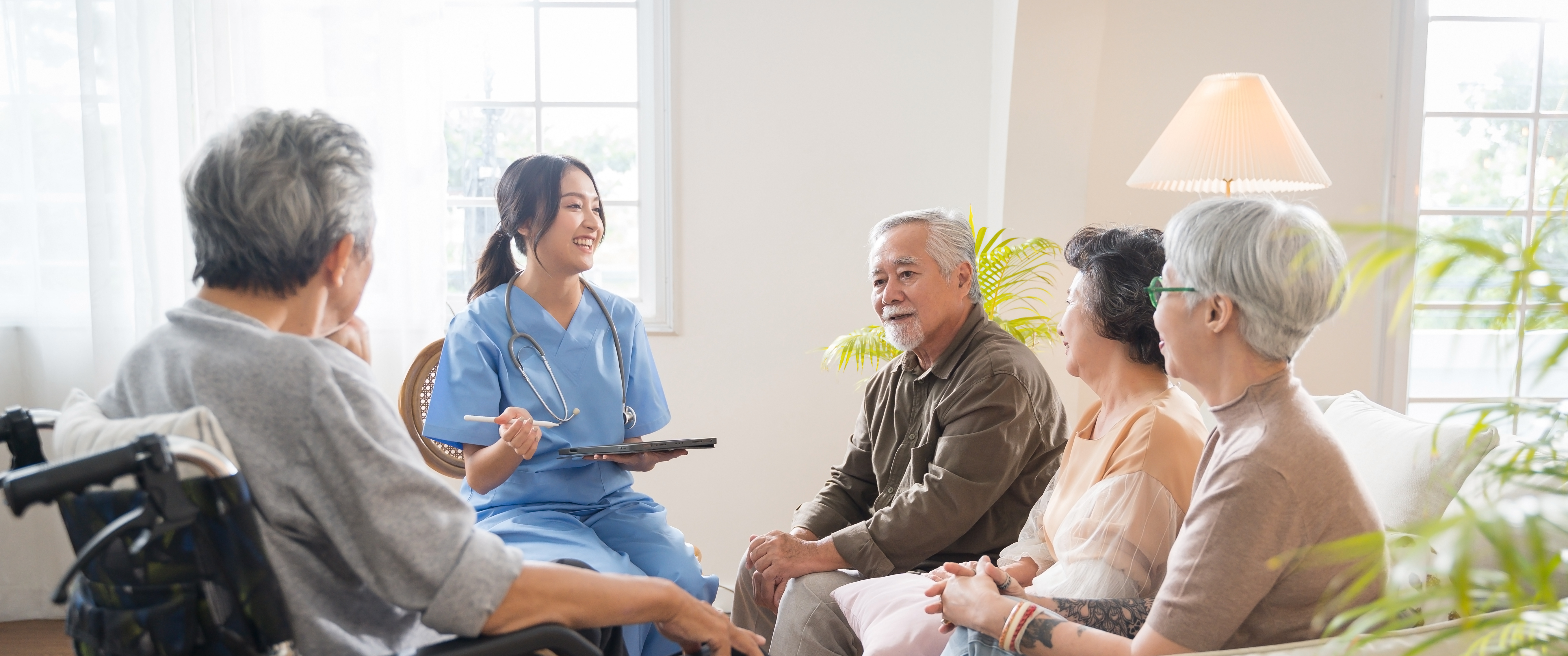 A group of Asian seniors sit and listen to a nurse