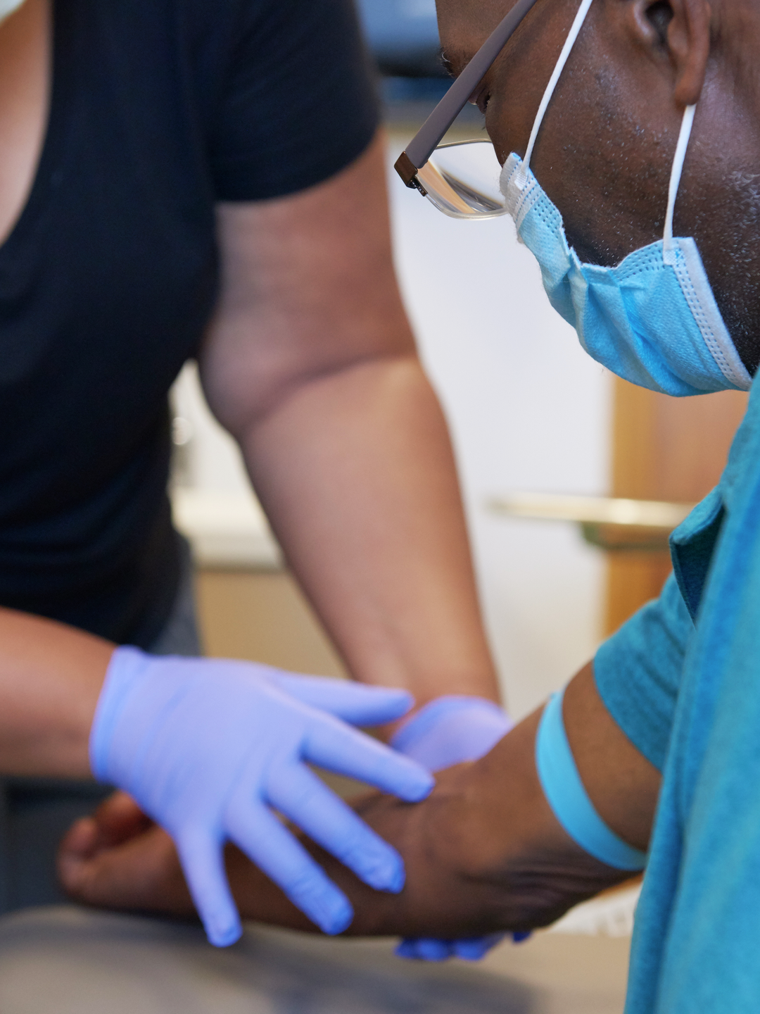 A medical assistant touches Nathaniel Williams' arm in preparation for drawing blood