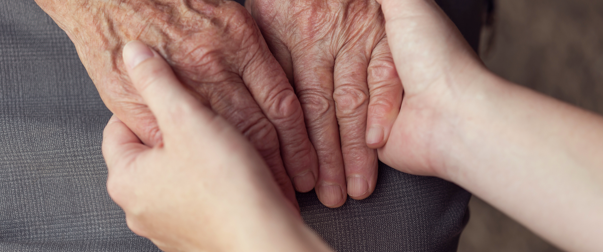 Old and young person holding hands. Elderly care and respect, selective focus