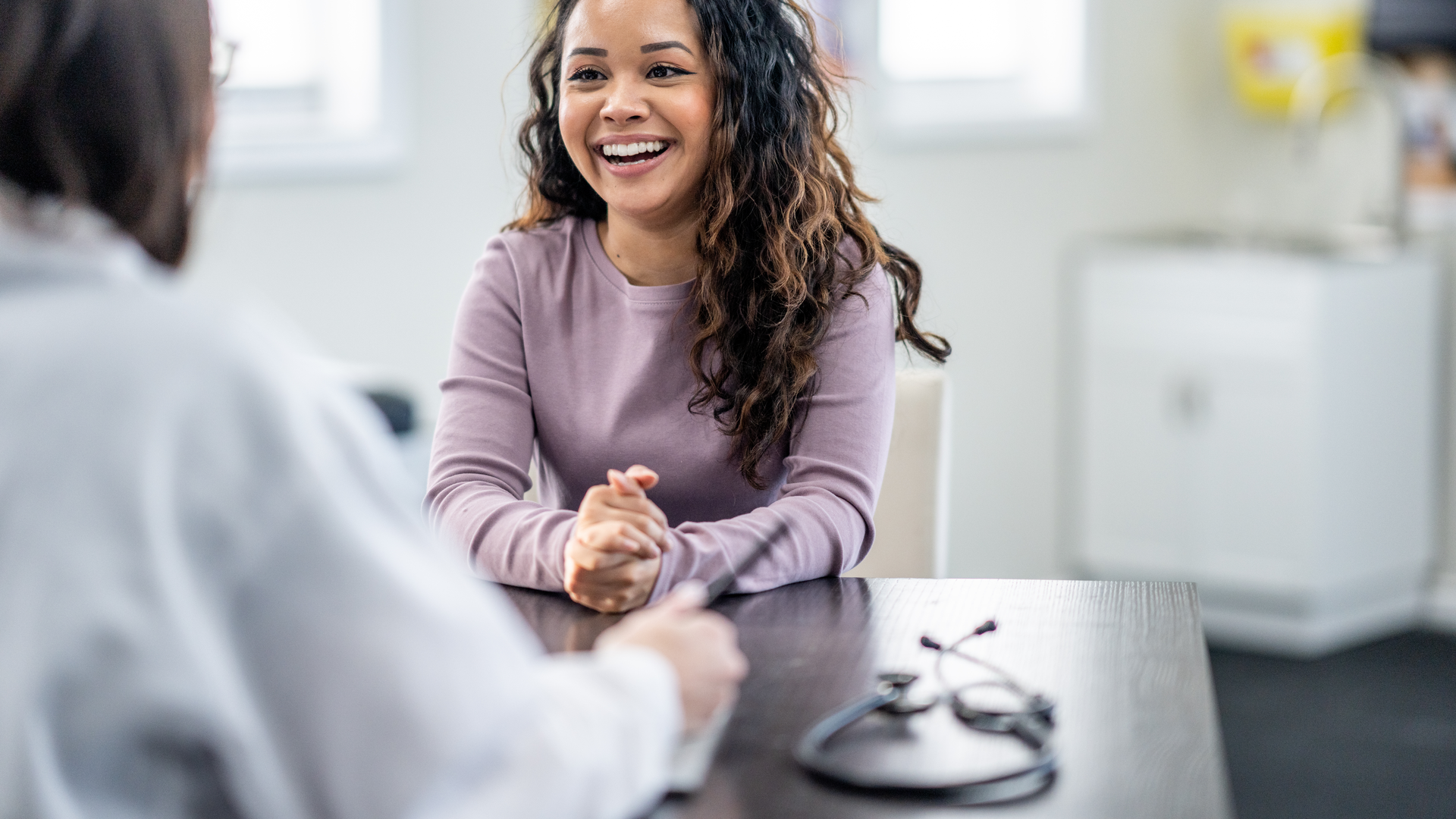 Young woman of mixed race, sits with female doctor discussing health concerns