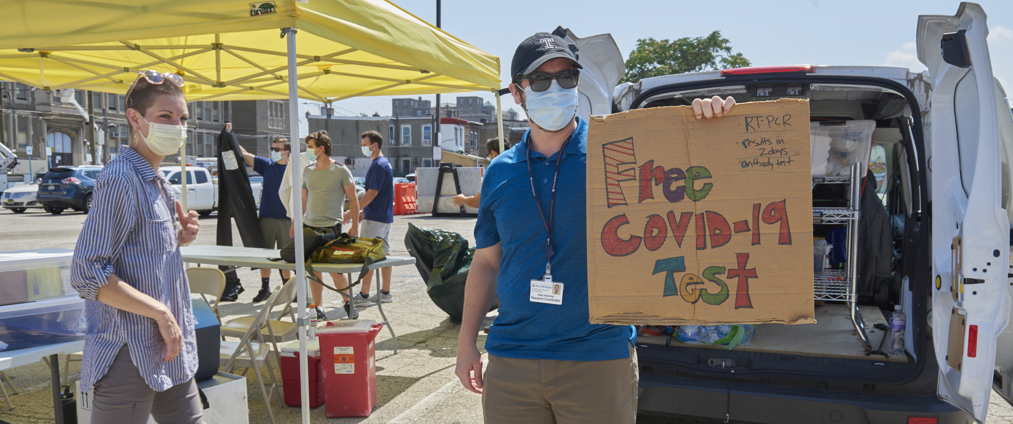 Nabil Abdulhay, MPH, holds a sign for free COVID testing at the Love Lot, with Rachel McFadden, BSN, beside their tent