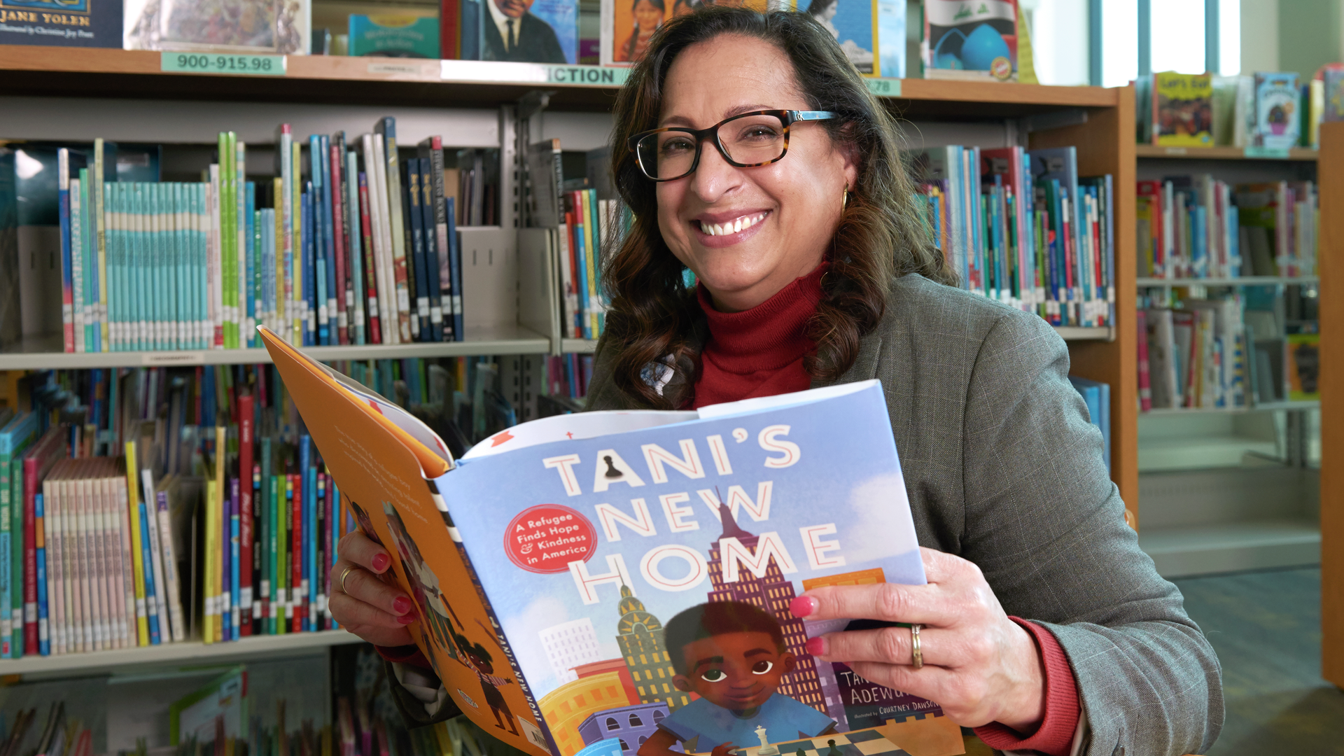 Evelin La Paz smiles while holding open a children's book