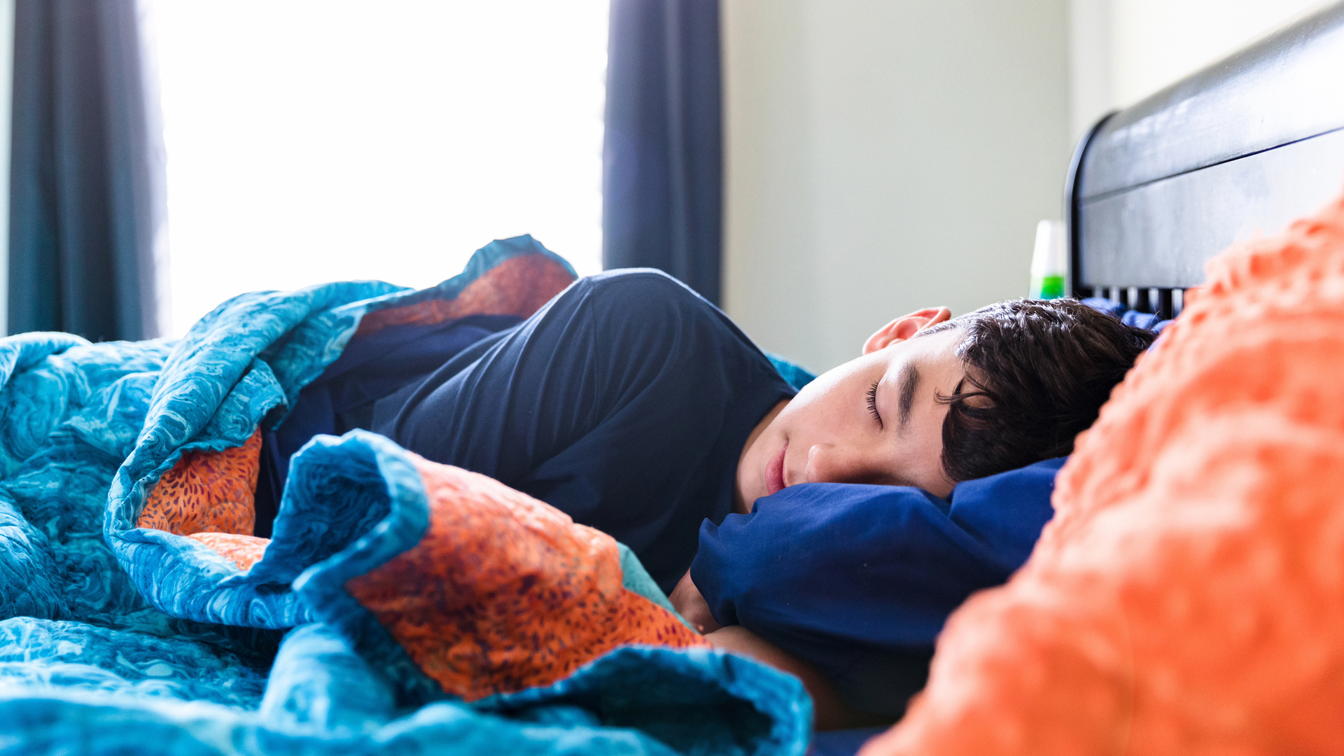 A teenage boy sleeping in a bed