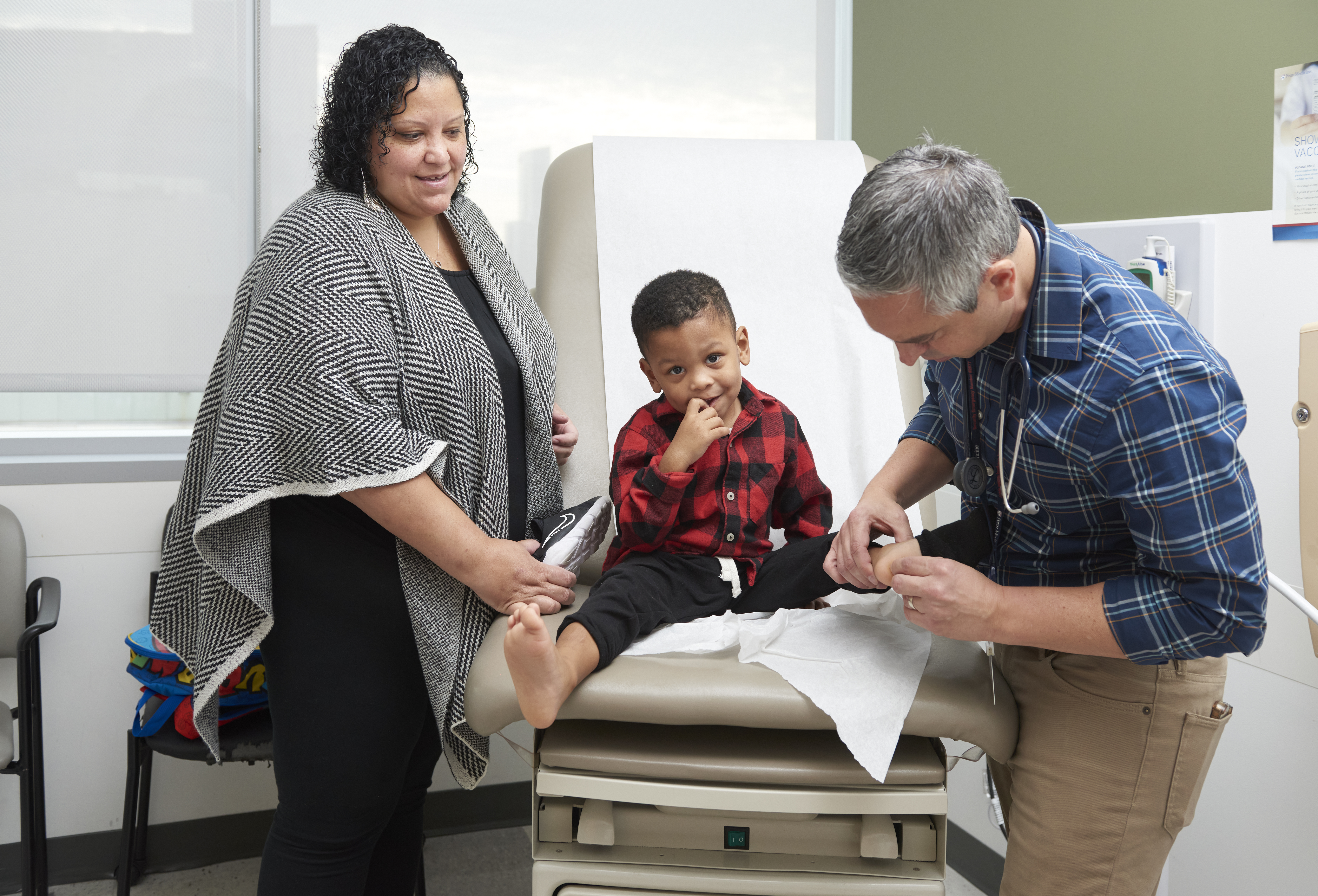 Nicole Miller watches as Mario DeMarco, MD, examines her 3-year-old son on an exam table